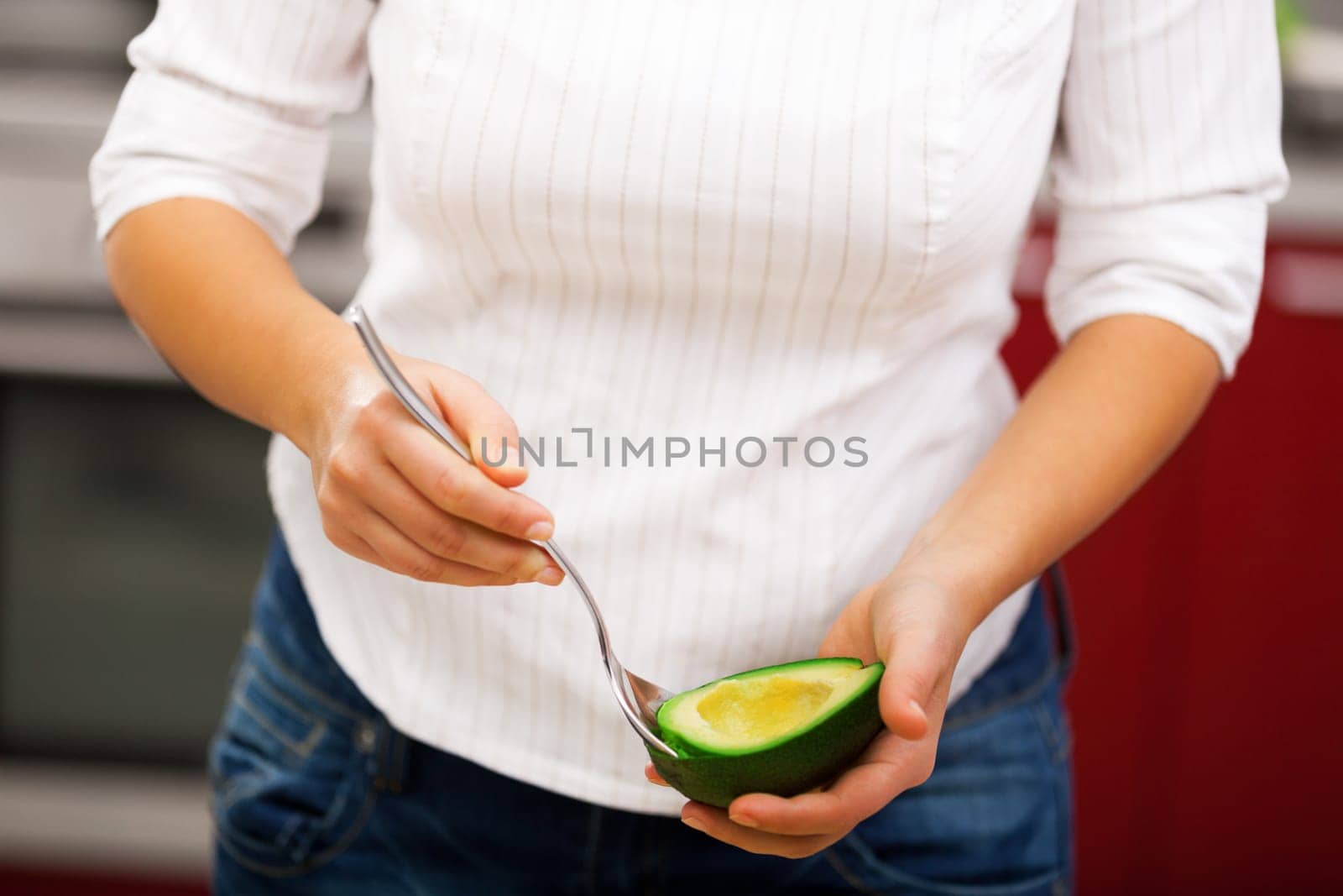Young woman making salad in the kitchen - peeling avocado