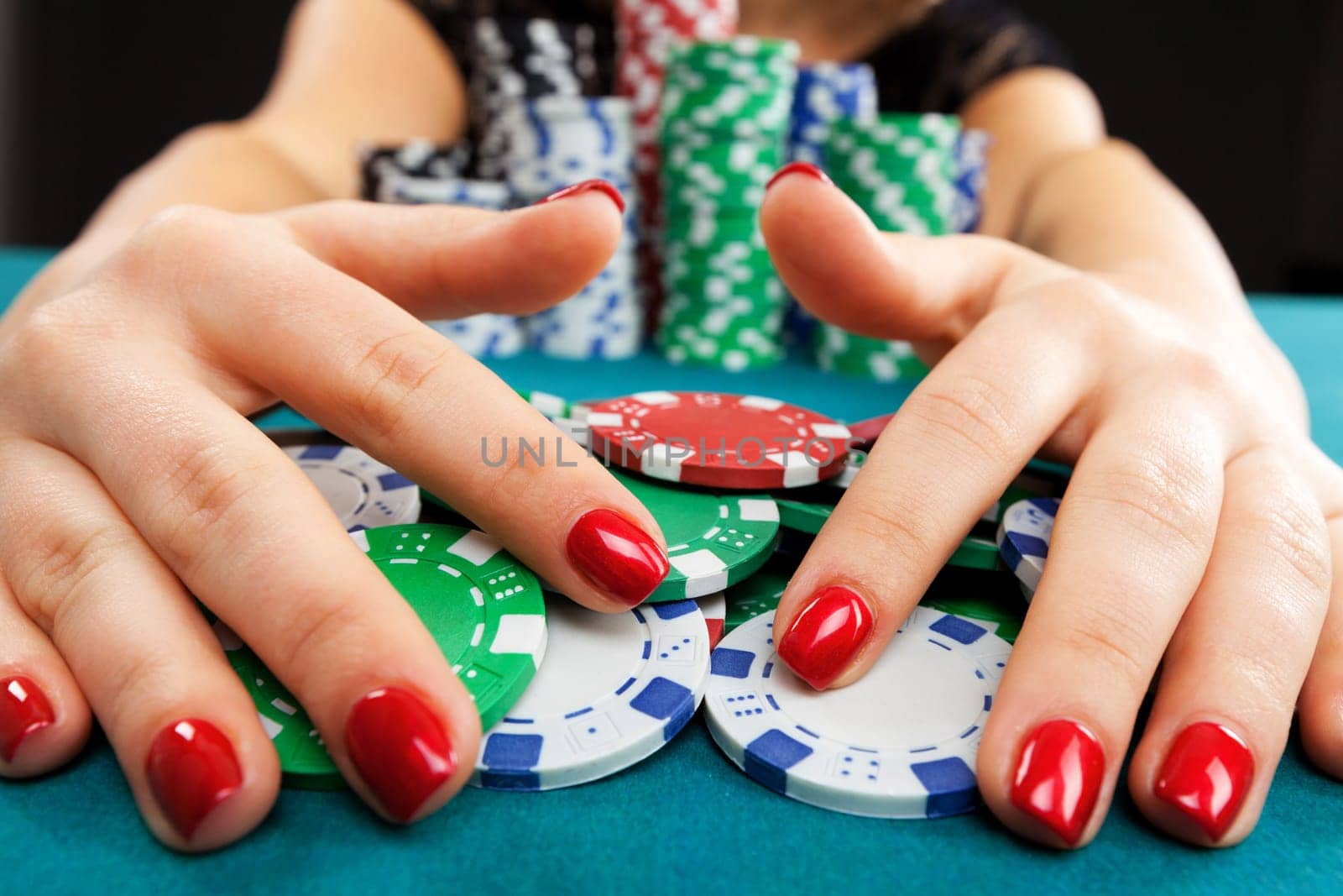 Young woman holding gambling chips on black background