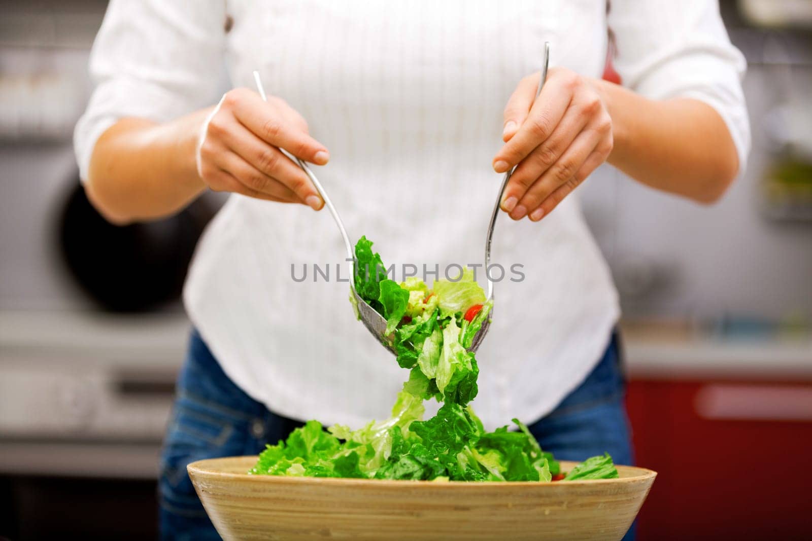 Young woman making salad in the kitchen