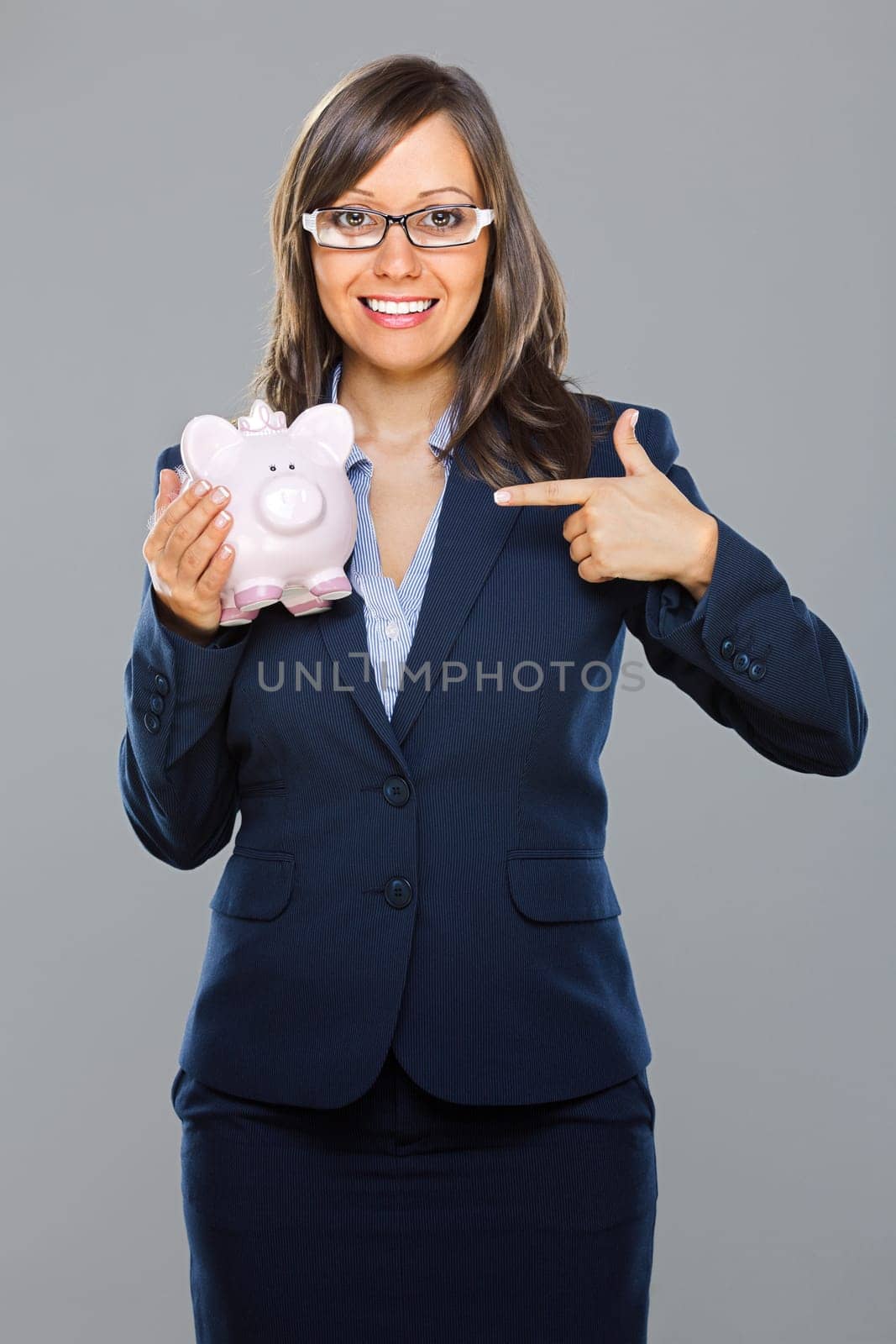 Businesswoman holding pink pig money-box isolated on gray background smiling