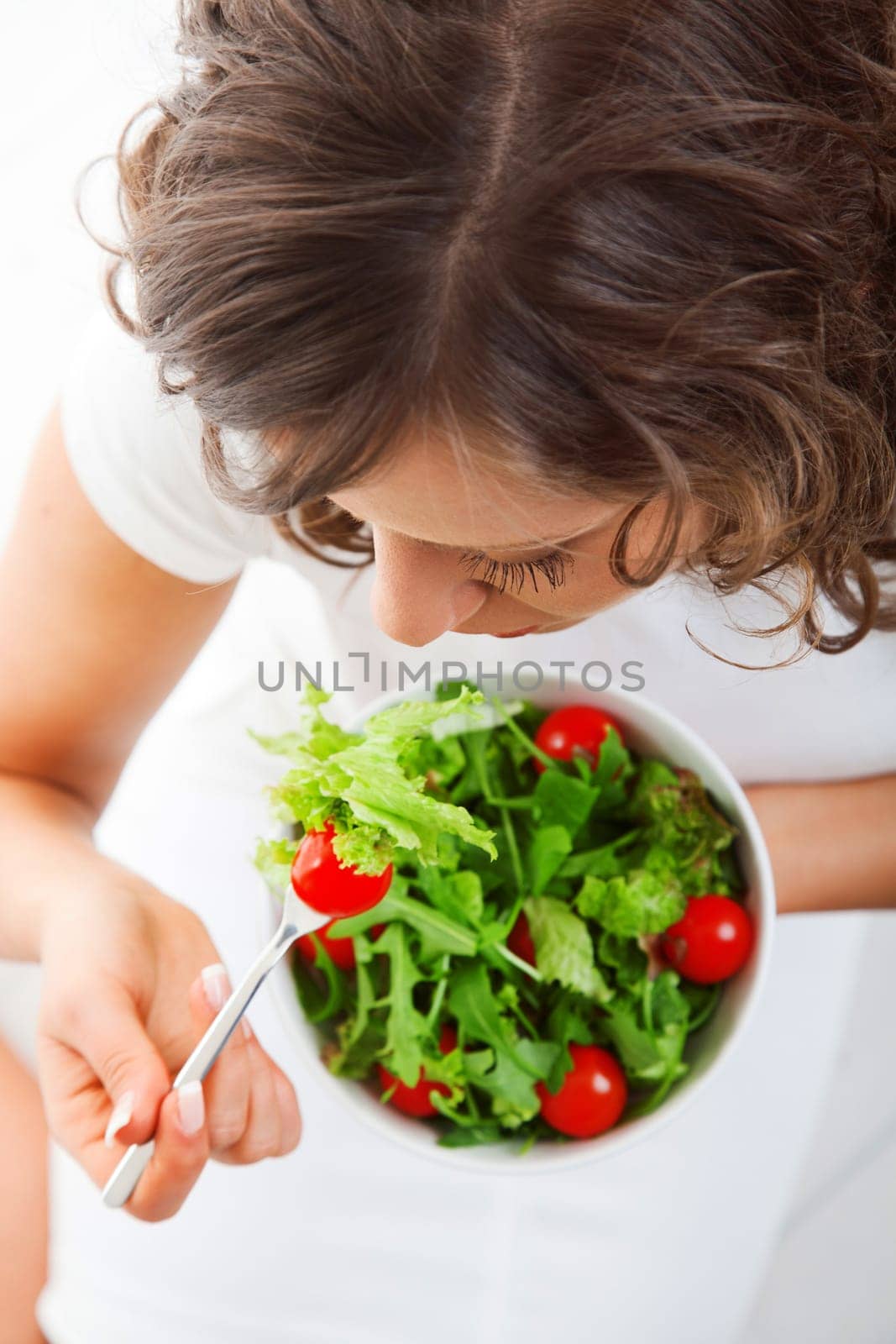 Youg woman eating healthy salad isolated on white background