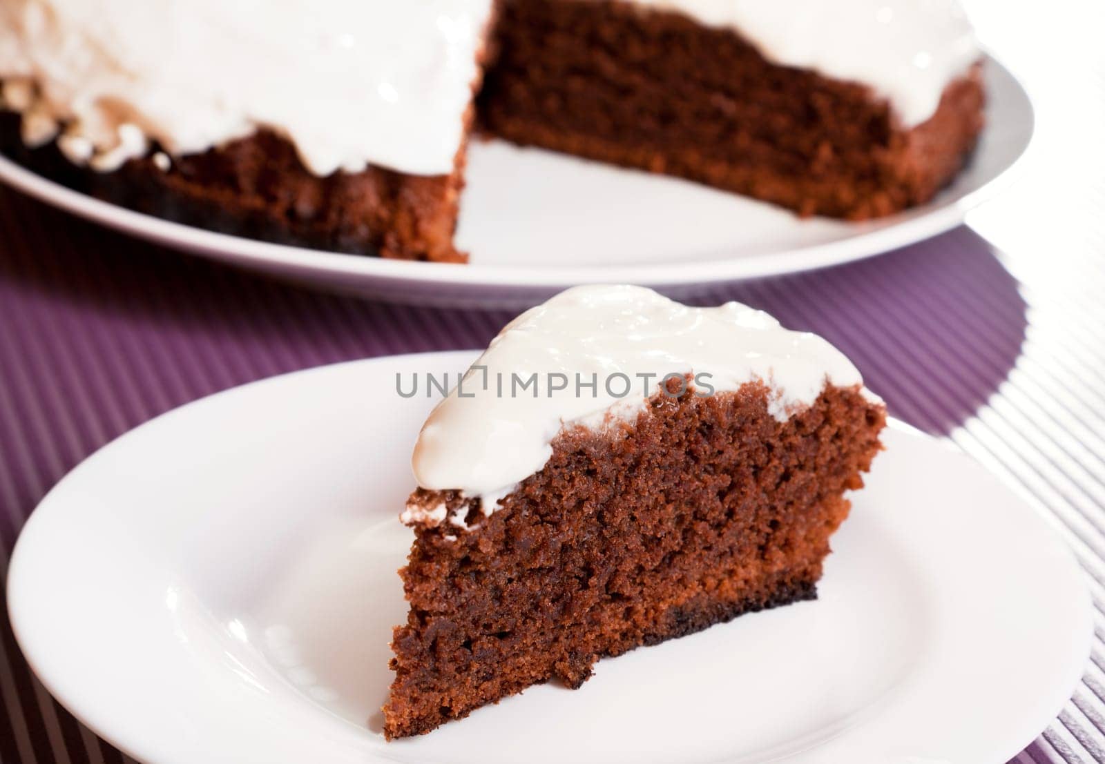 Chocolate cake with white cream, with one piece cut from the whole cake