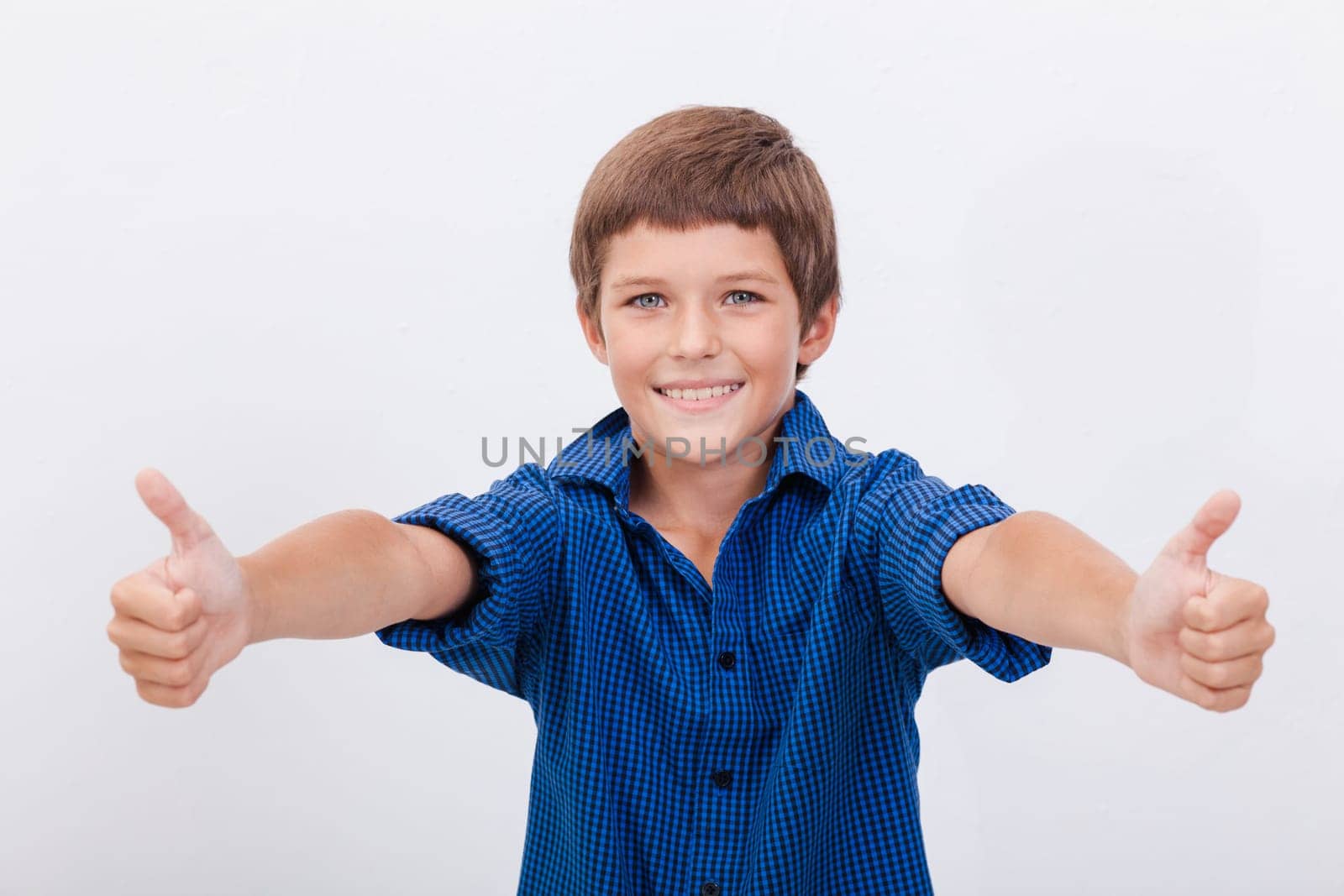 Portrait of happy boy showing thumbs up gesture,  over white background