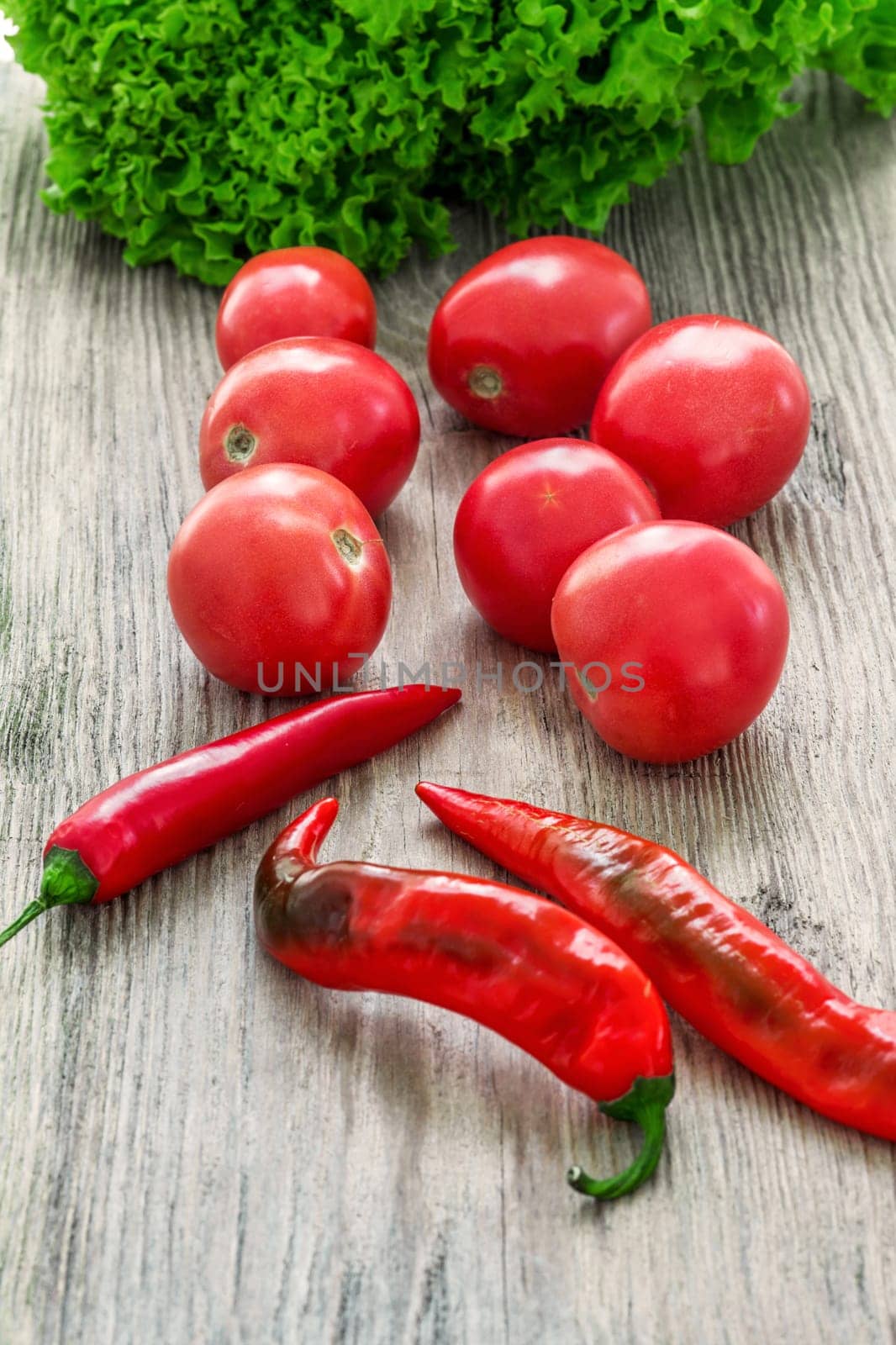 The set of multicolored vegetables on wooden table - tomatoes, peppers, lettuce