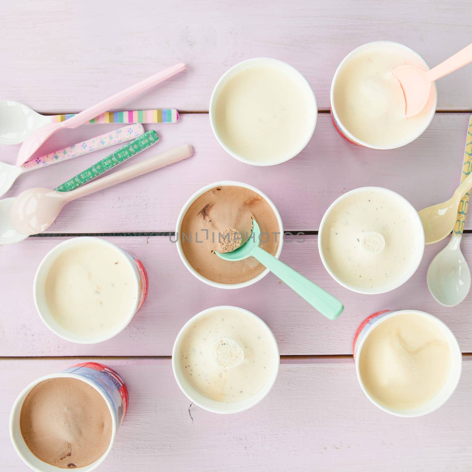 Various small cardboard cups with ice cream and colourful loeffeln