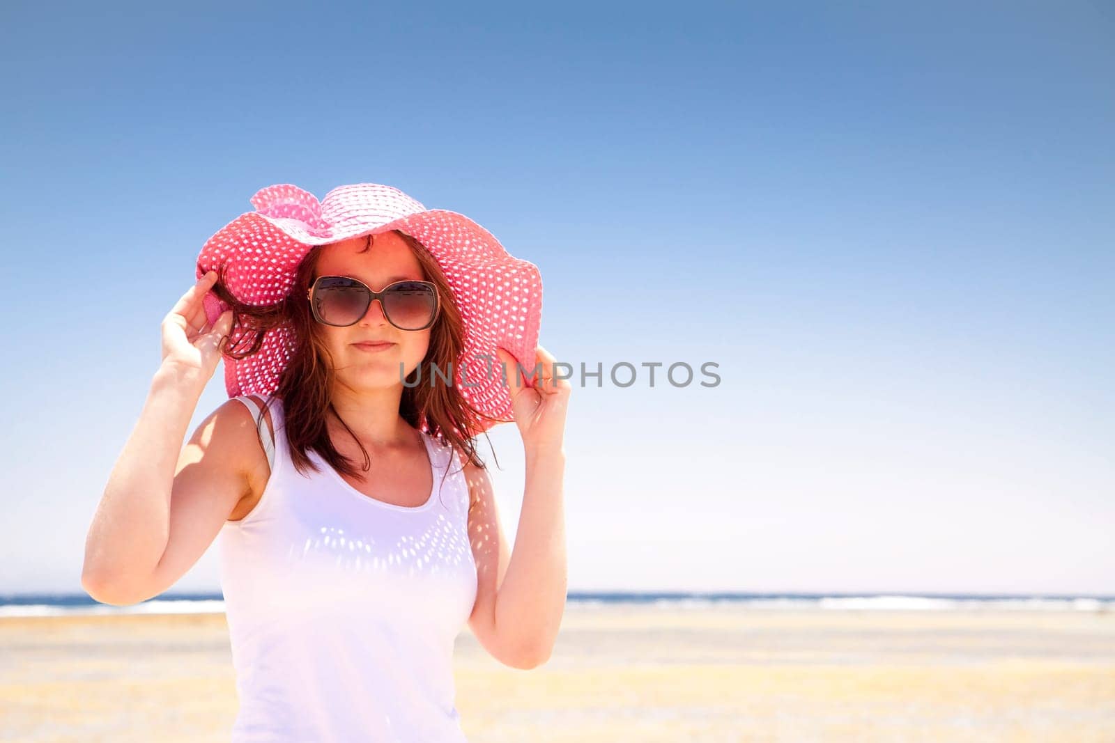 Woman in a pink hat on the sunny beach.