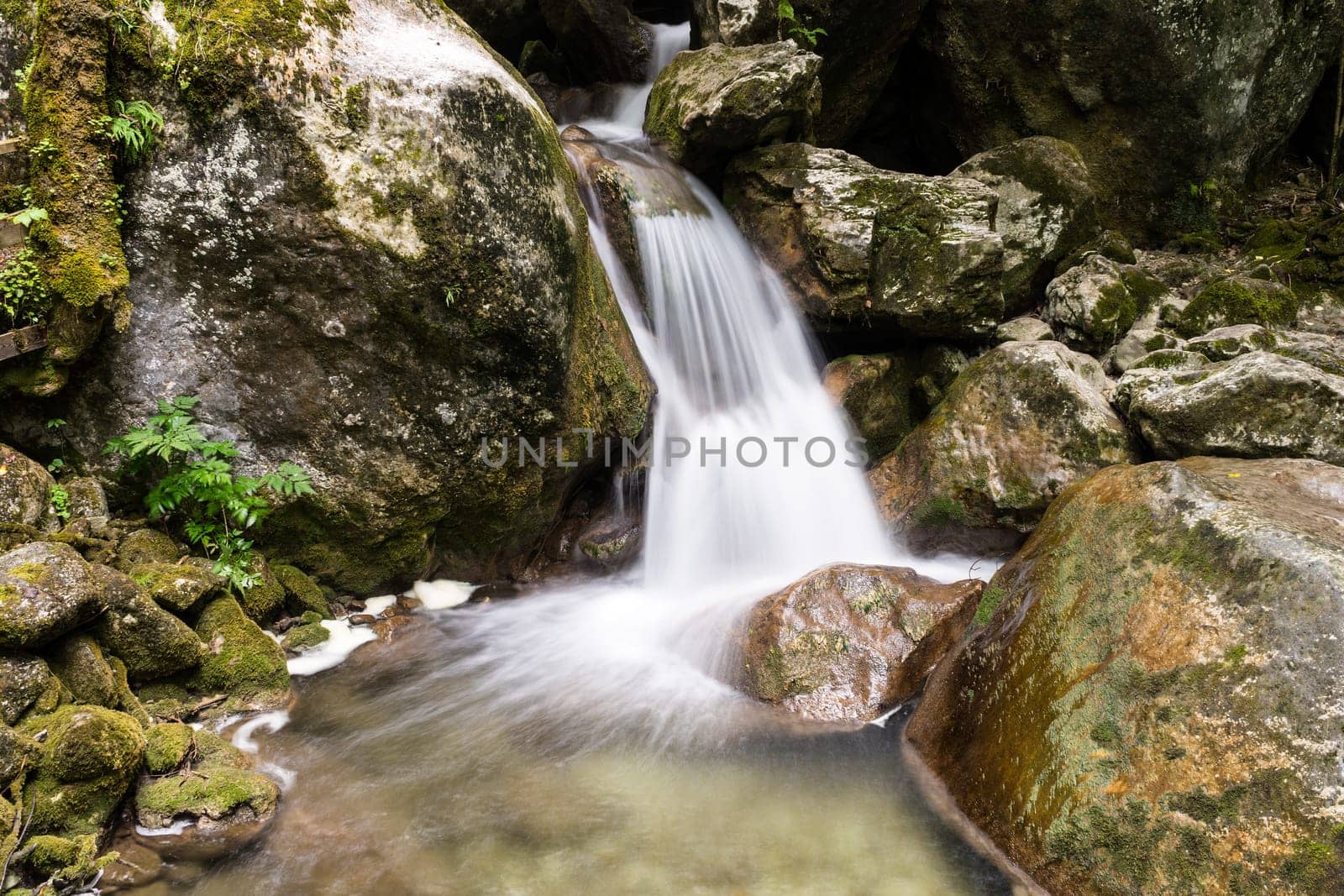 Waterfall mountain river,blurred water between stones with moss