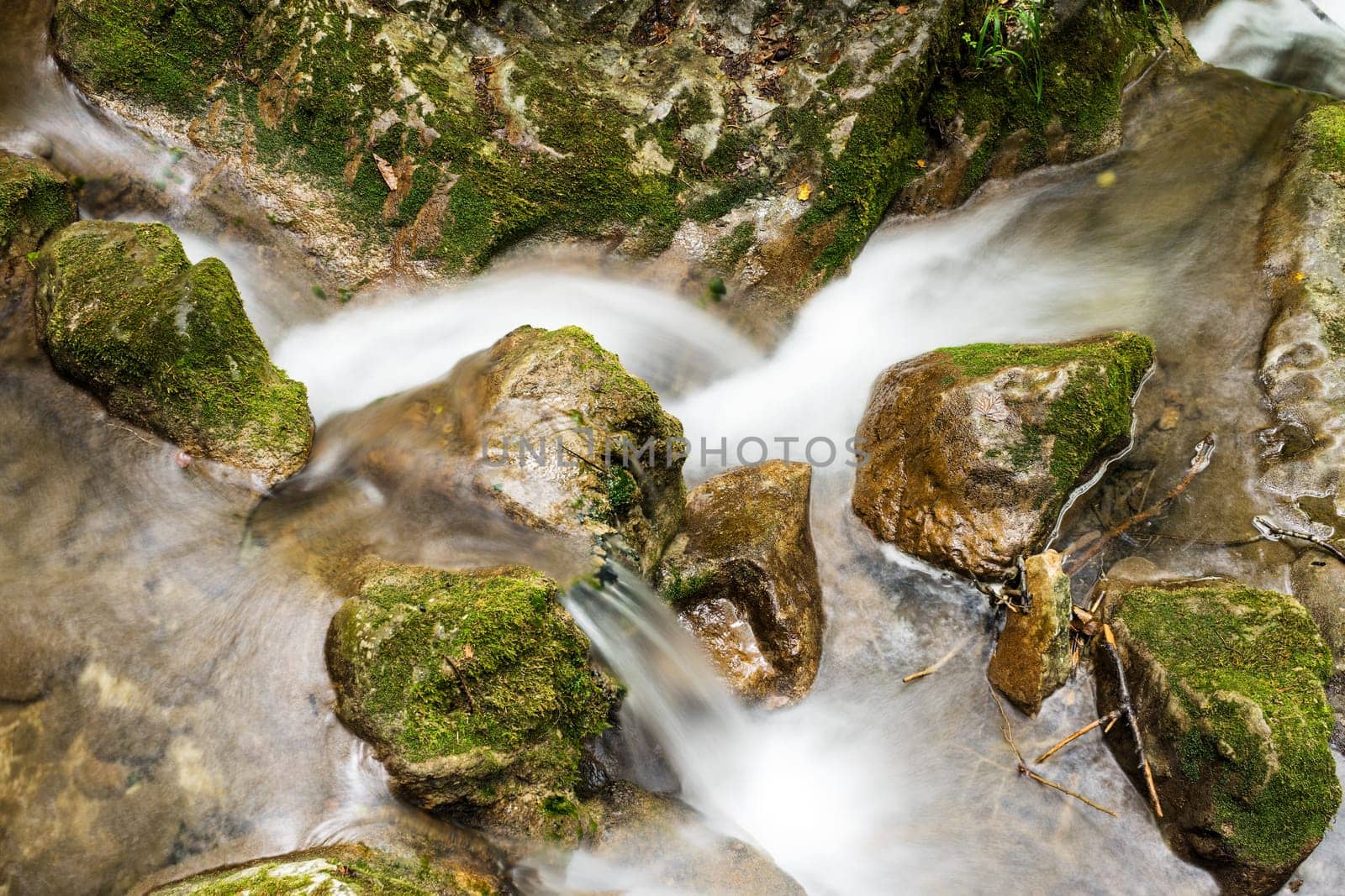 Waterfall mountain river,blurred water between stones with moss