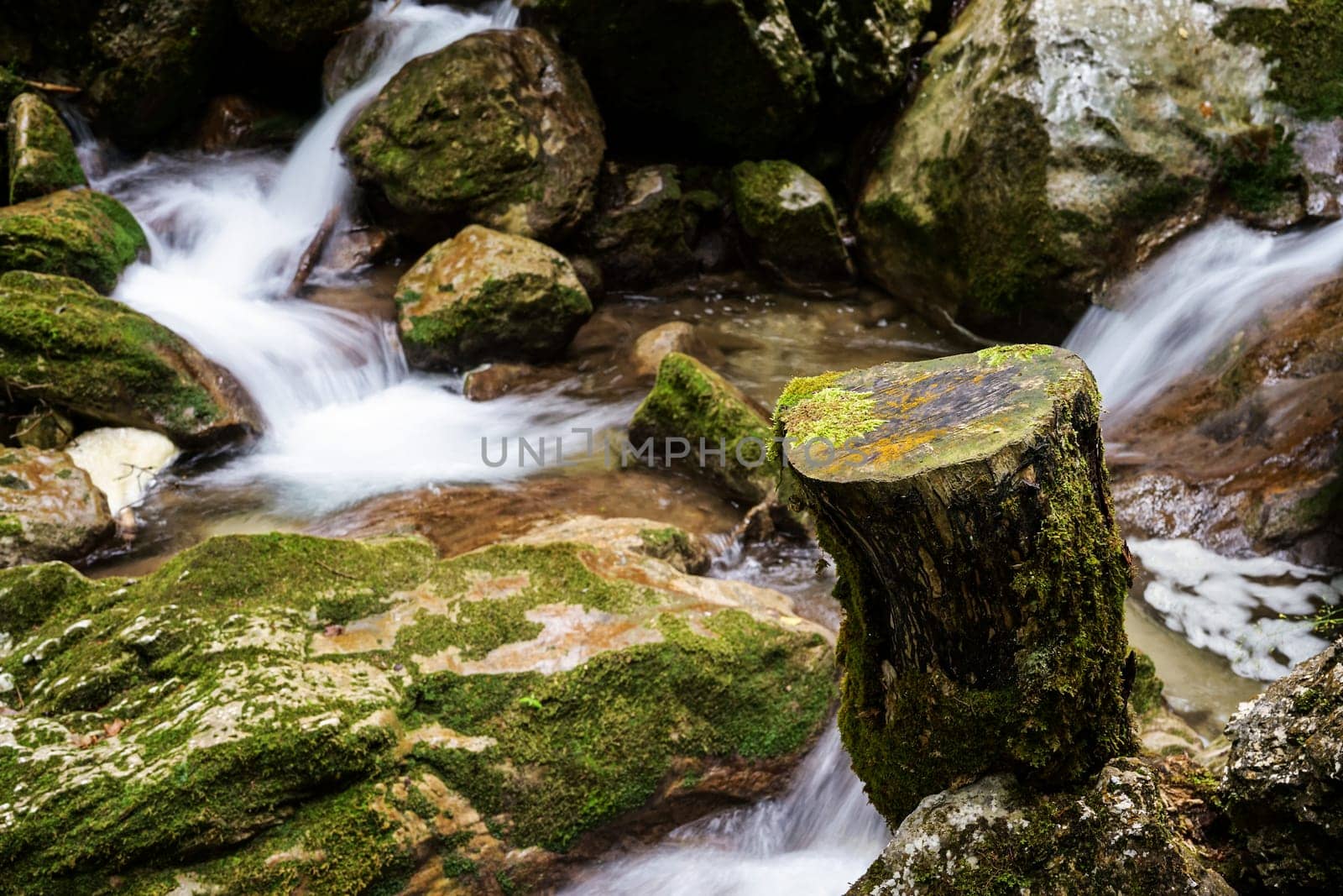 Waterfall mountain river,blurred water between stones with moss