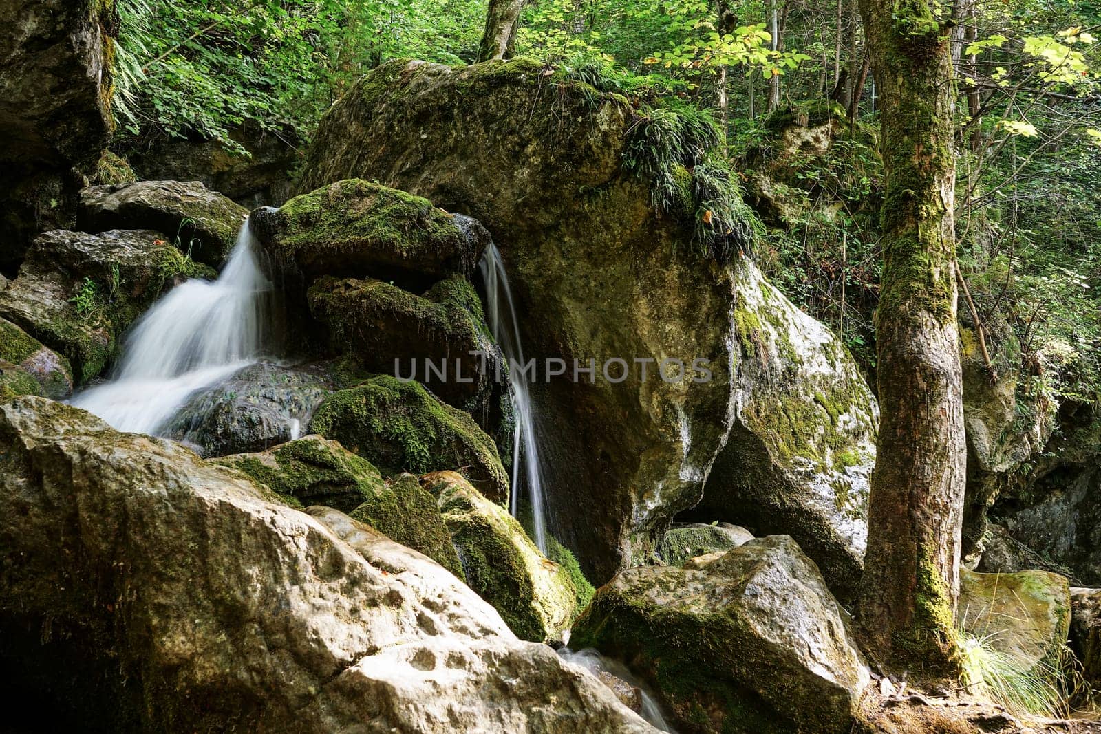 Waterfall mountain river,blurred water between stones with moss