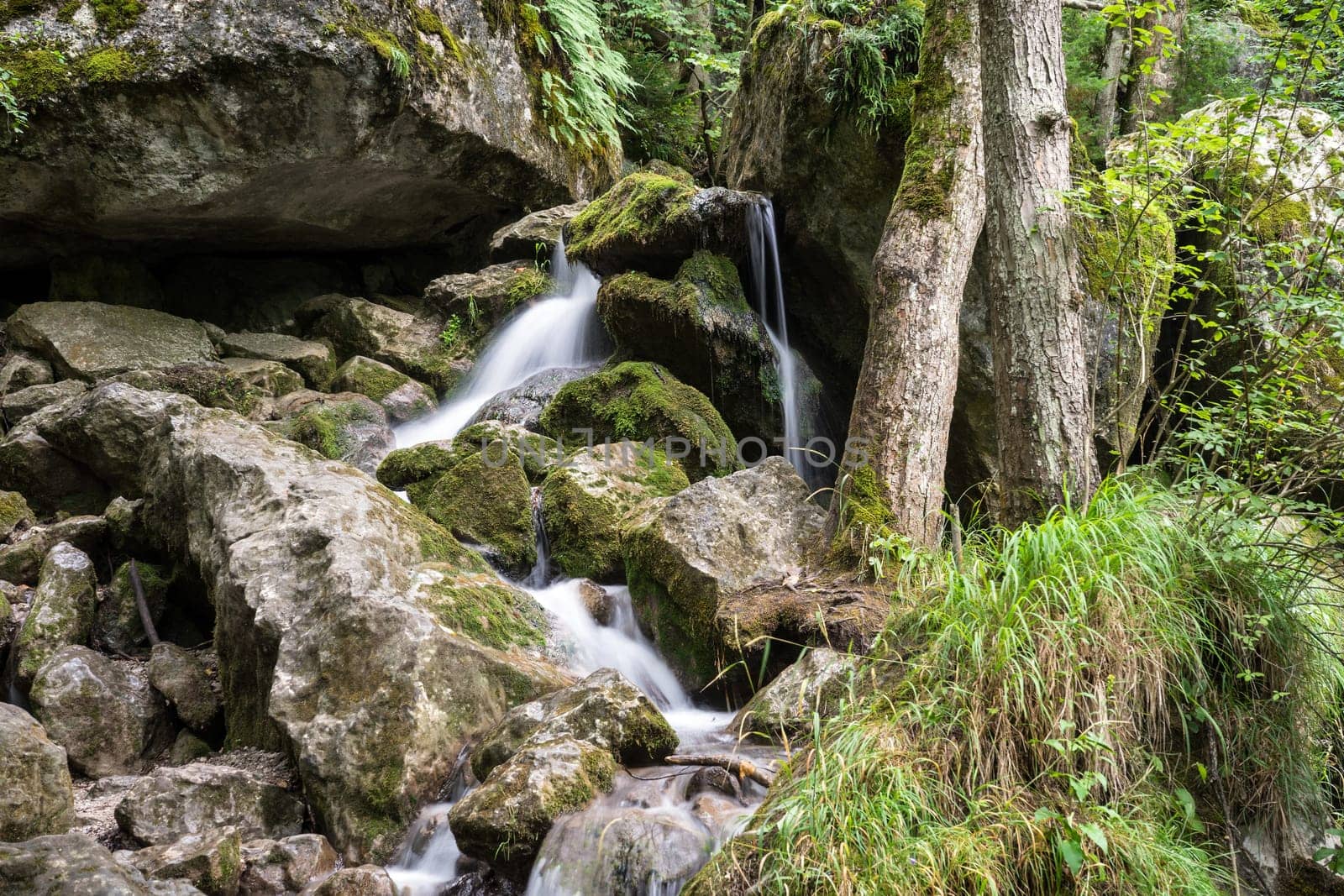 Waterfall mountain river,blurred water between stones with moss