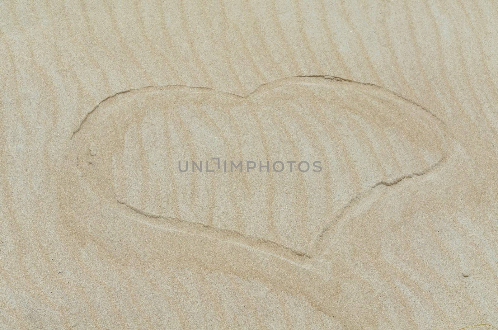 Heart drawn in the sand. Beach background. Plan.