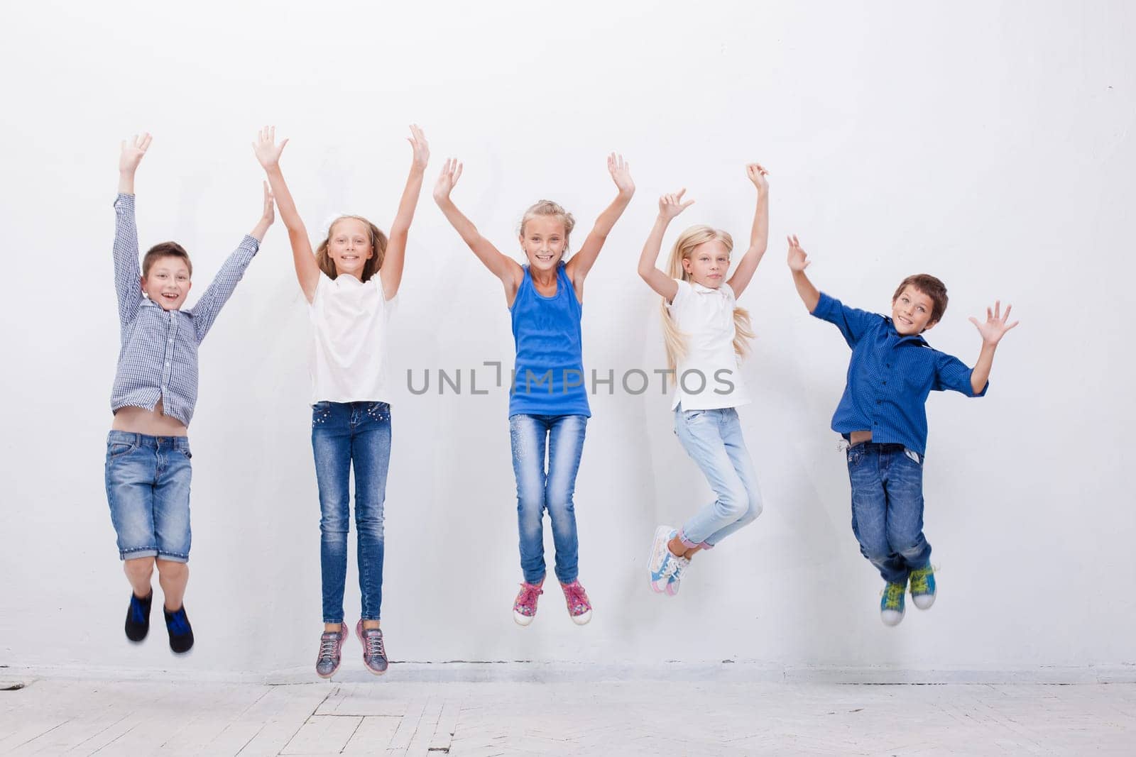 Group of happy young teens jumping over a white background