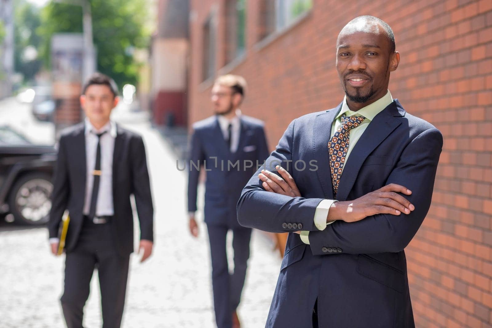 Portrait of multi ethnic business team. Three happy smiling men standing against the backdrop of the city.  The foreground of a African-American man