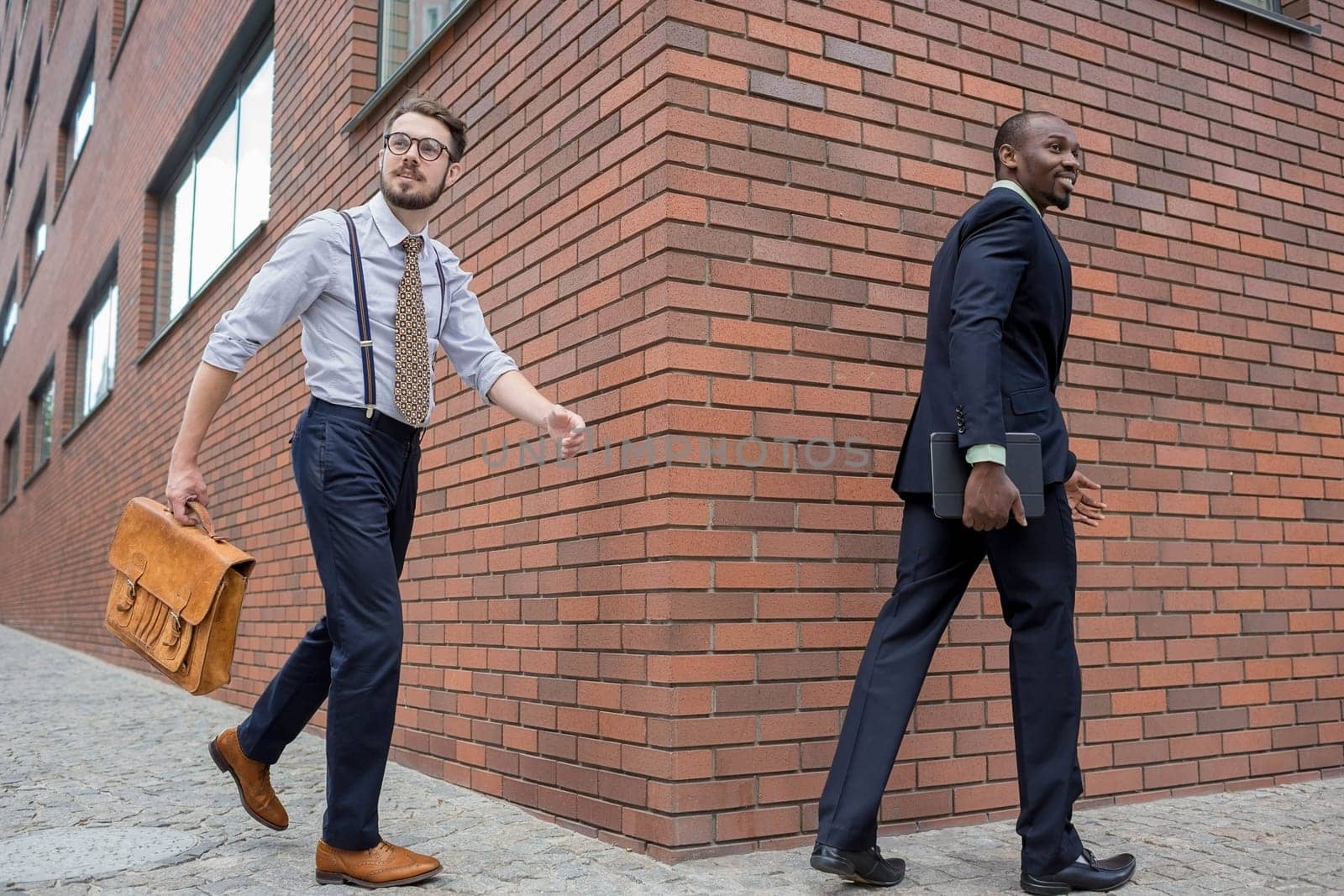 Portrait of multi ethnic business team. Two happy smiling men  walking against the backdrop of the city. The one man is African-American, other is European. concept of business success