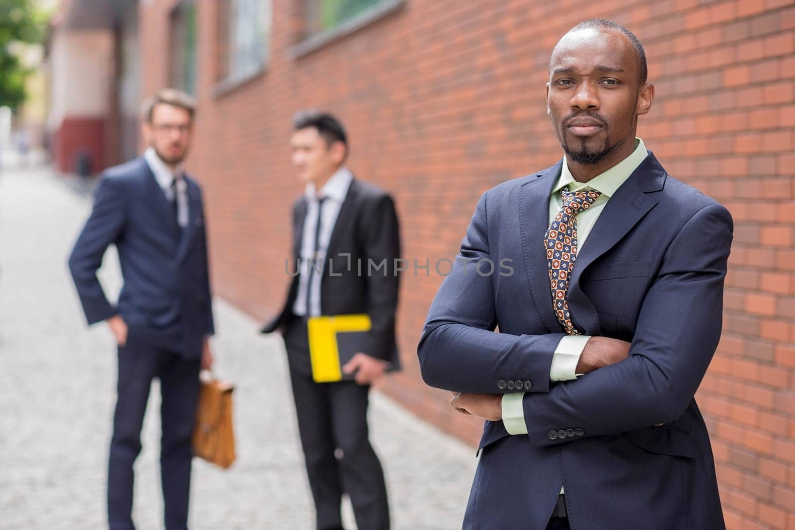 Portrait of multi ethnic business team. Three happy smiling men standing against the backdrop of the city.  The foreground of a African-American man