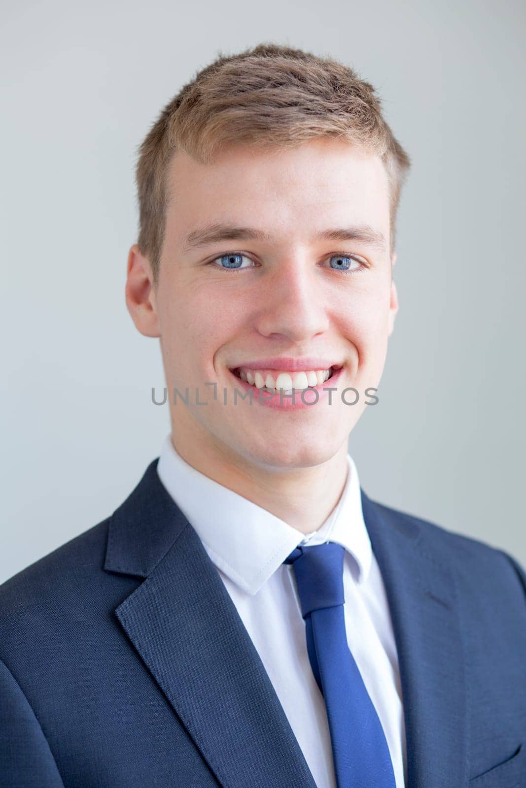Close up portrait of a formally presented young man, smiling for the camera on a white background