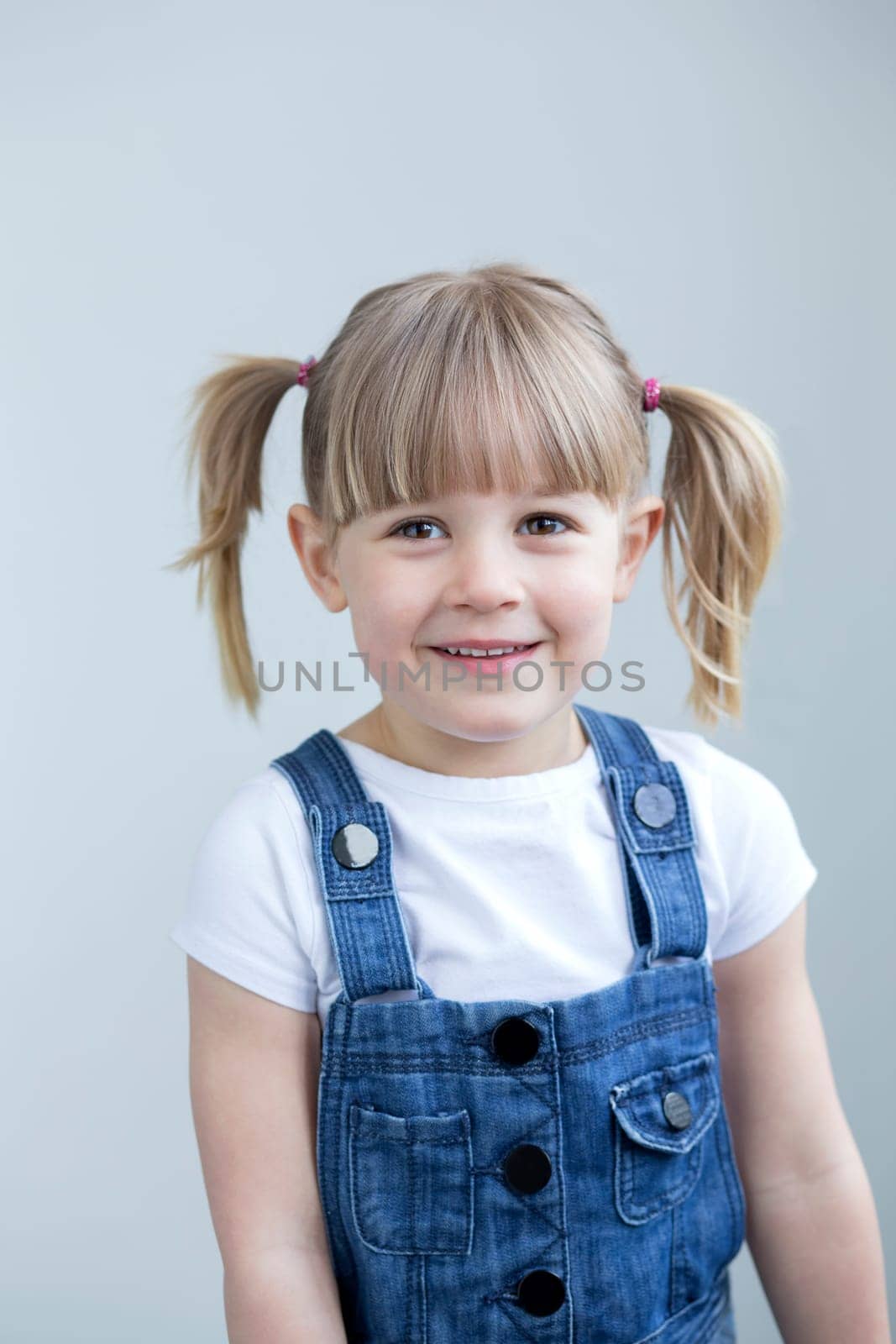 Cute young girl in dungarees smiling at the camera