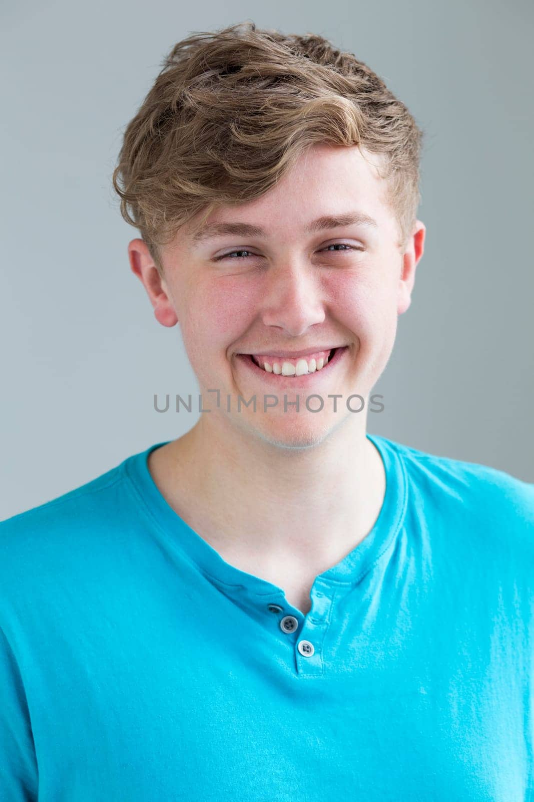Portrait of a teenage boy against a plain background. He is smiling for the camera.