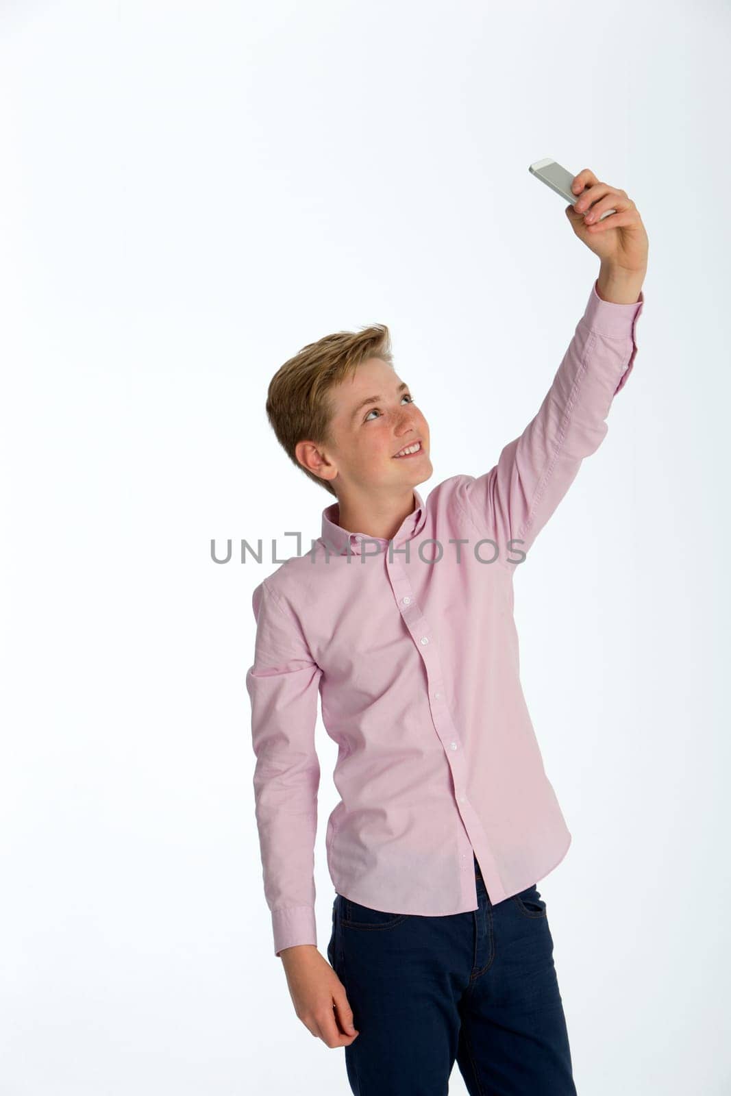 Young boy taking a selfie on a smartphone against a white background