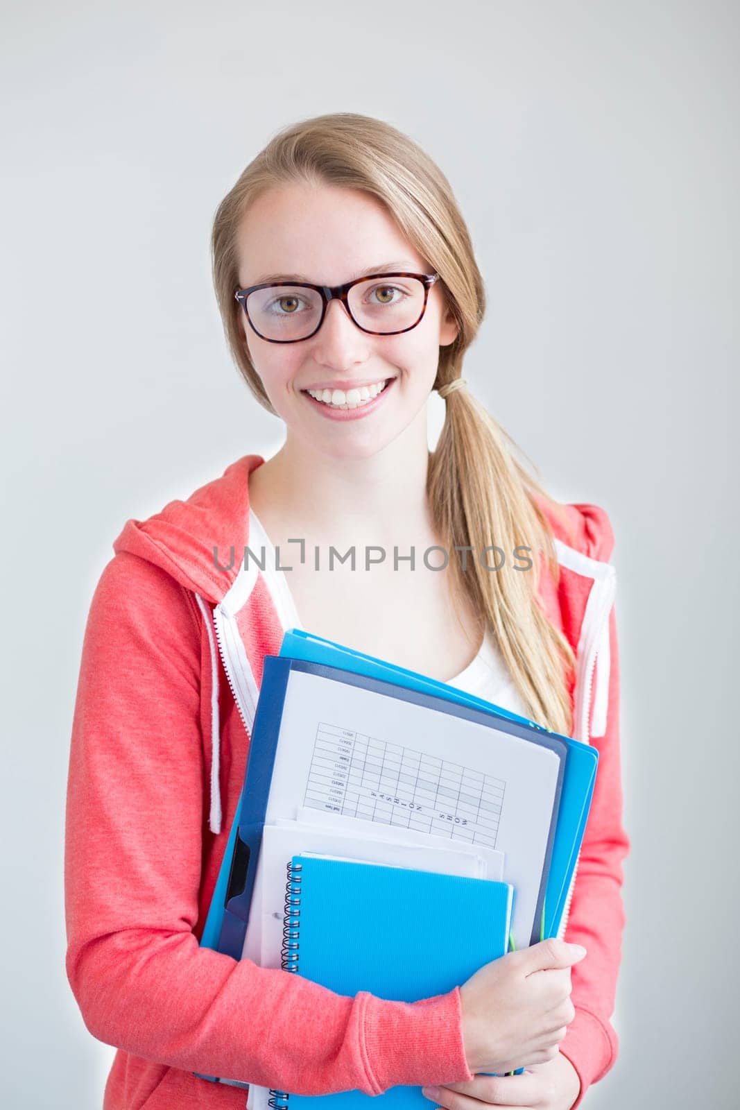 Portrait of an attractive young girl on a white background. She is holding folders and paper work.