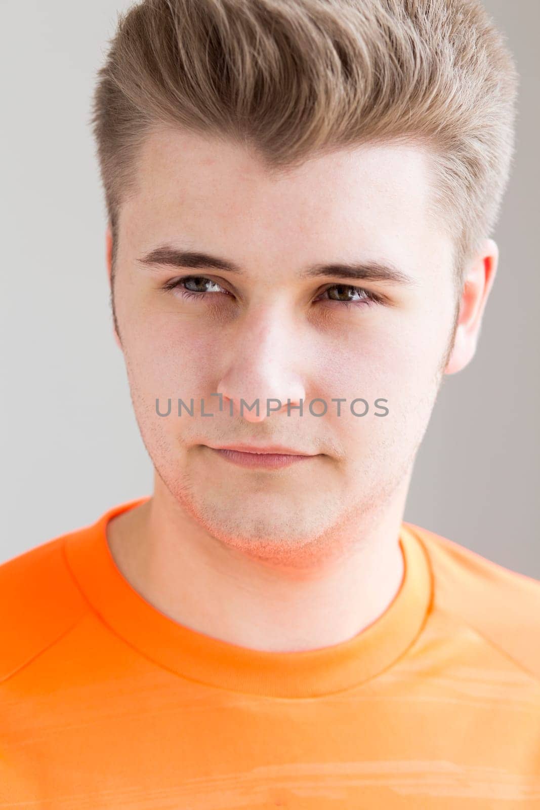 Close up portrait of an attractive young man against a plain background.