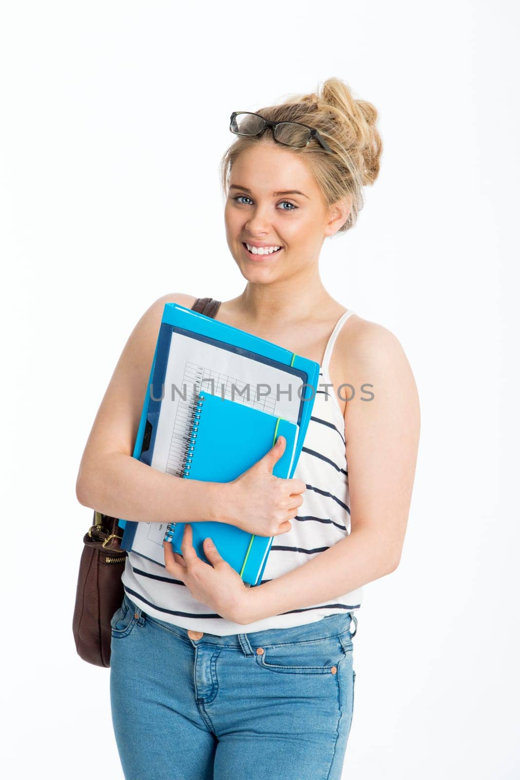 Teenage girl with folders in her hand. She is smiling for the camera and standing against a white background.