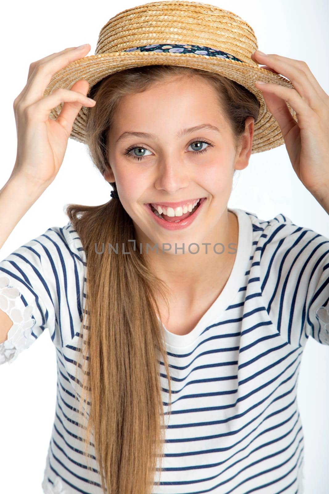 Beautiful girl posing with a straw hat against a white background.