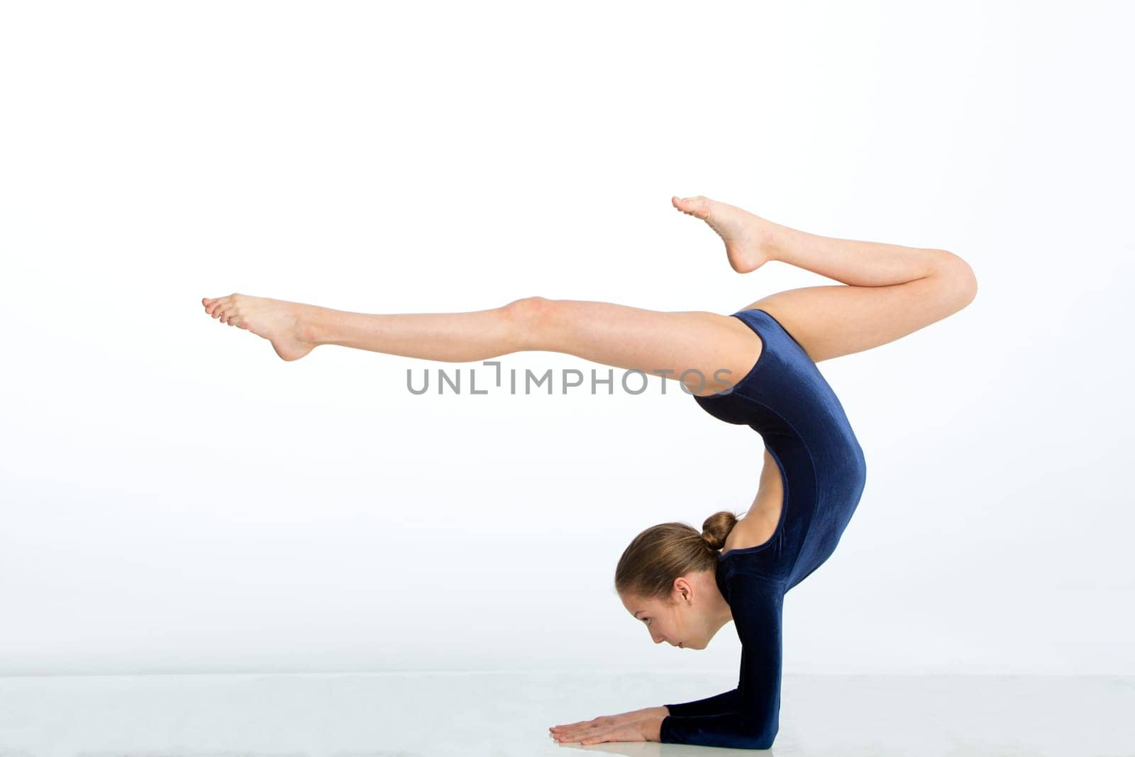 Female gymnast balancing in a pose on her arms against a white background.