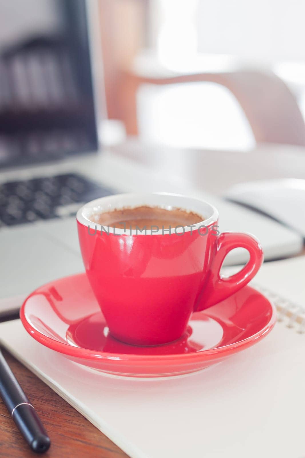 Red coffee cup with notepad and laptop, stock photo