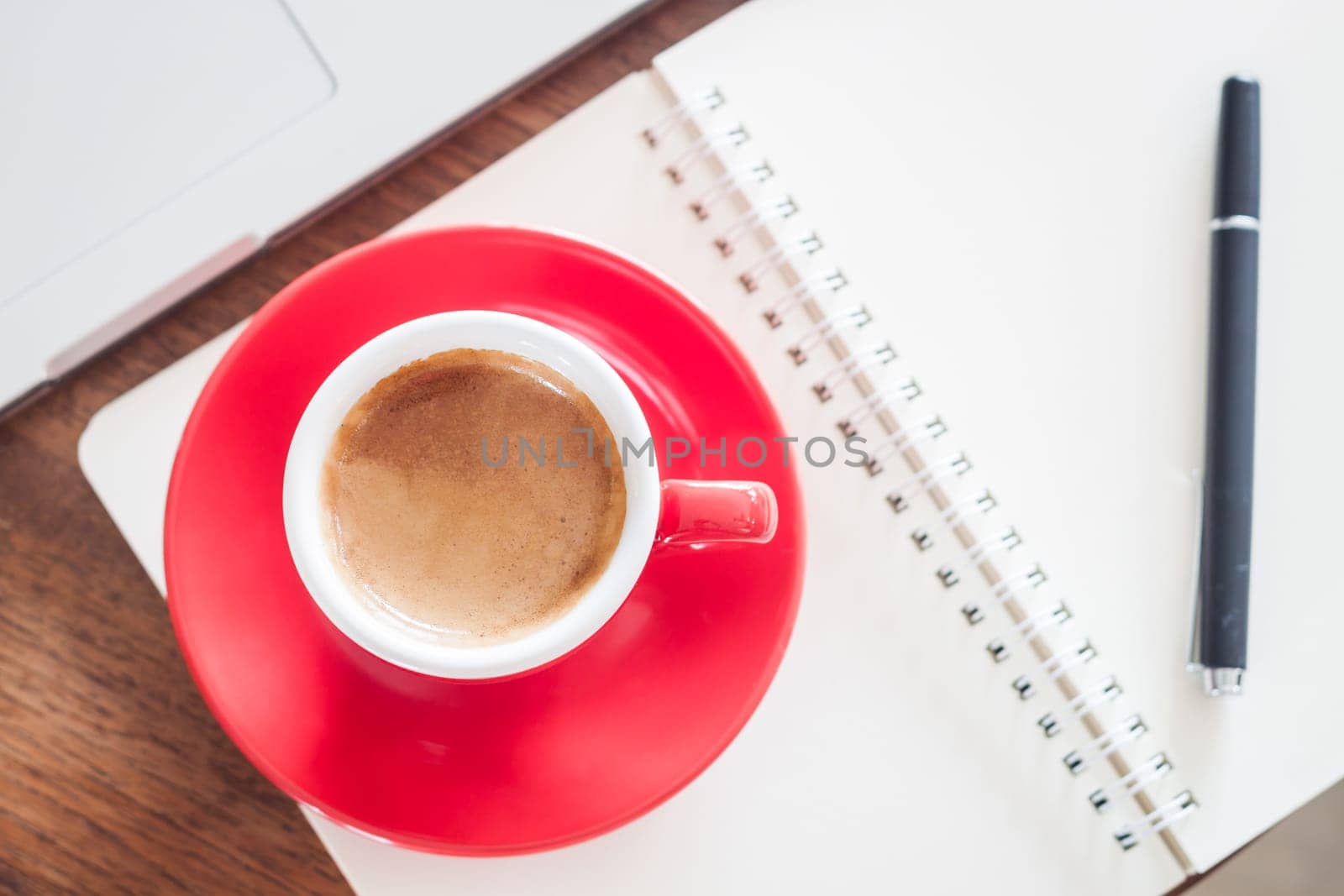 Red coffee cup with notepad and laptop, stock photo