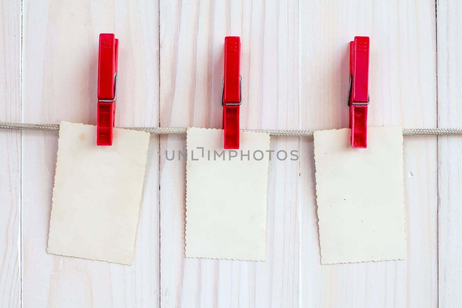 Photo frames hanging on a rope over white wooden background