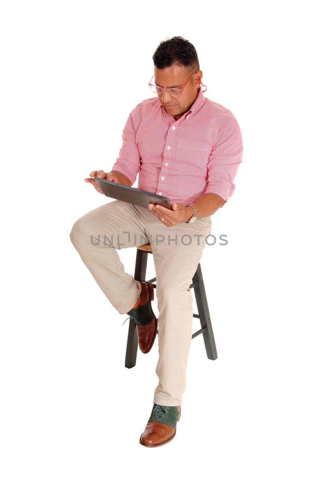 A middle age man sitting on a chair with safety glasses and earplug's working.with his tablet computer, isolated for white background..