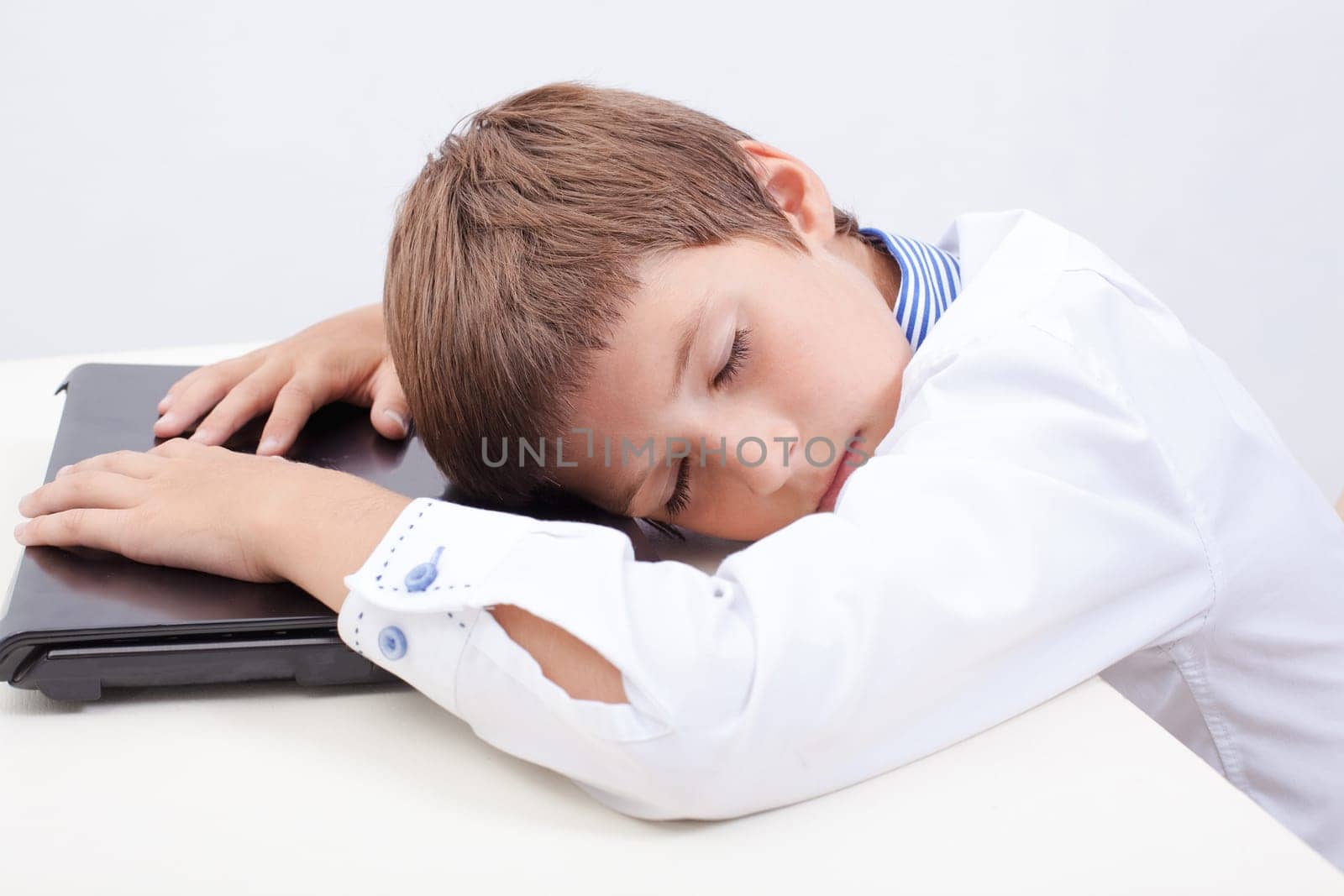 The tired boy using his laptop computer and slipping on white background.