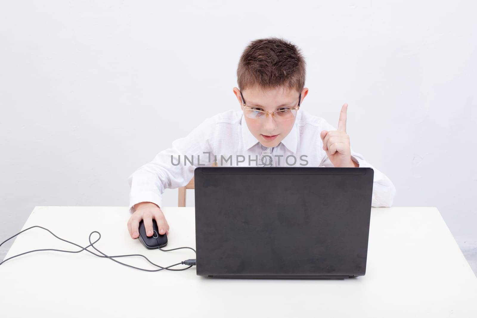 The boy with glasses using his laptop computer on white background.