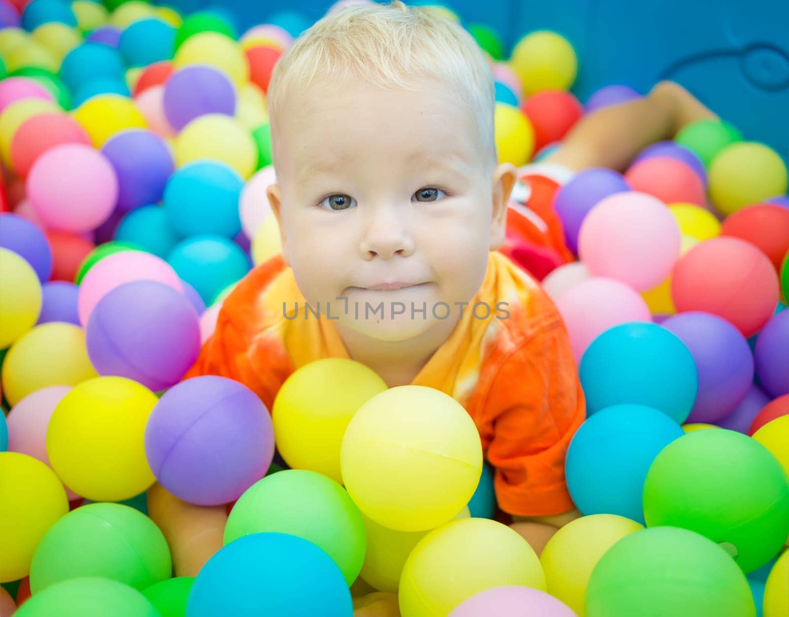 Cute kid boy playing with colorful balls