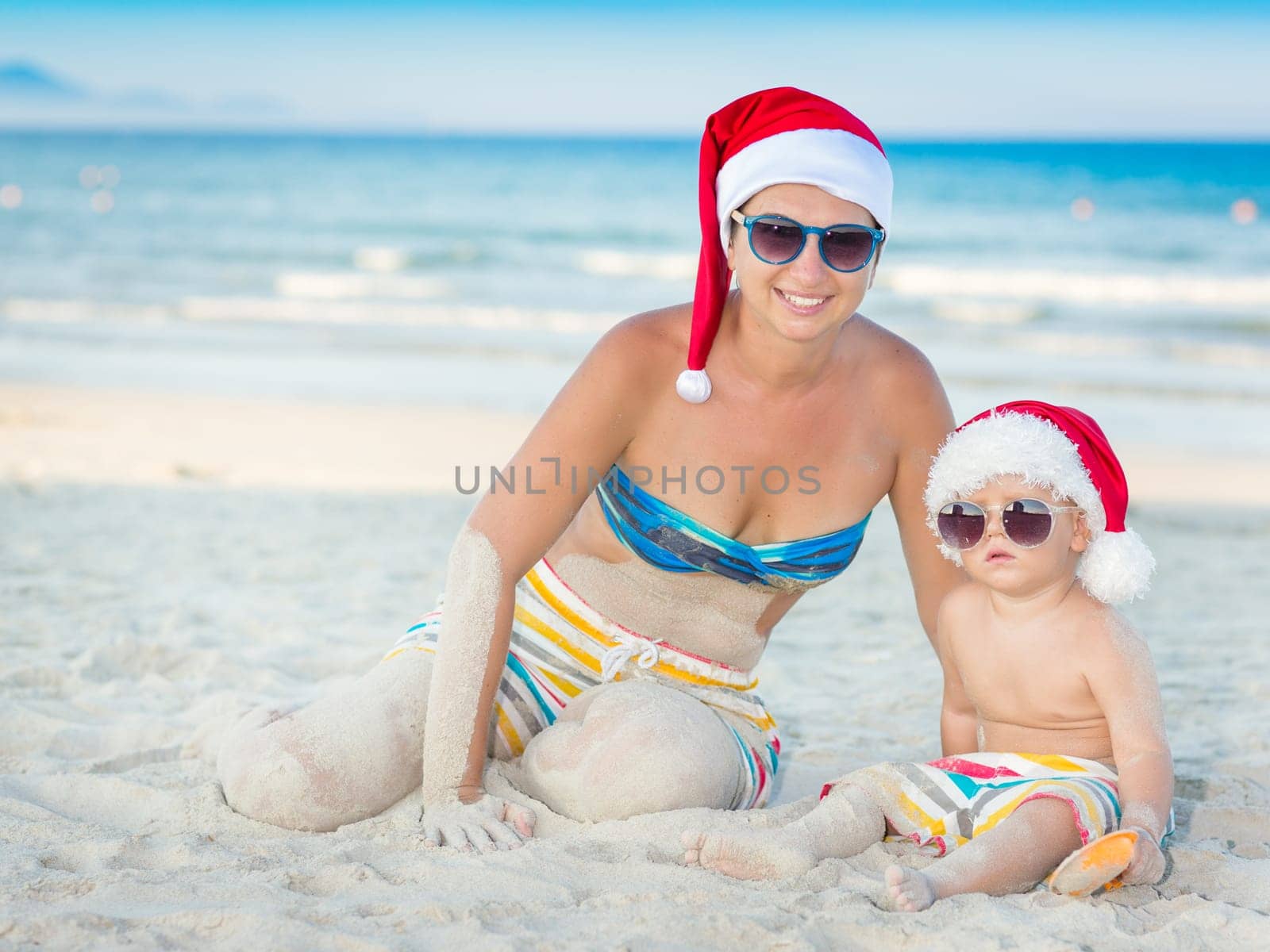 Baby and mother on the beach. Christmas concept