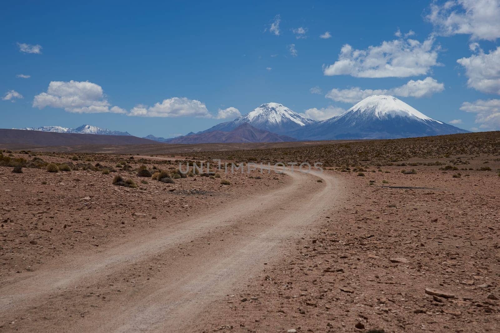 Snow and ice covered peaks of the volcanoes Parinacota (6342m) and Pomerape (6240m), tower above the altiplano in Lauca National Park, northern Chile.