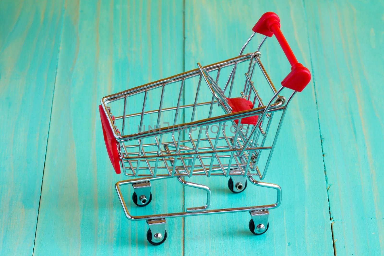 Empty mini shopping cart on the blue wooden background