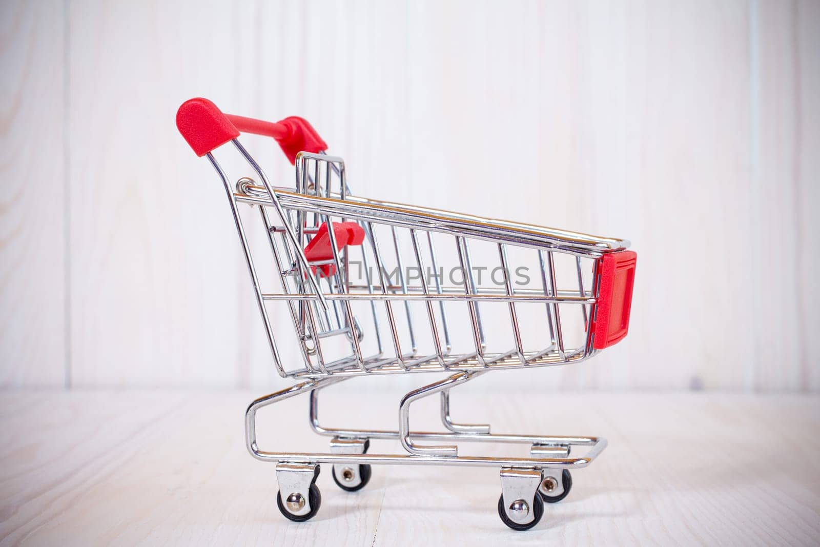 Empty shopping cart on white wooden background. Side view
