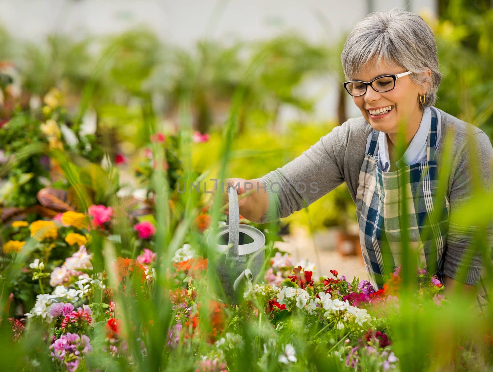 Beautiful mature woman gardening and looking at camera while smiling