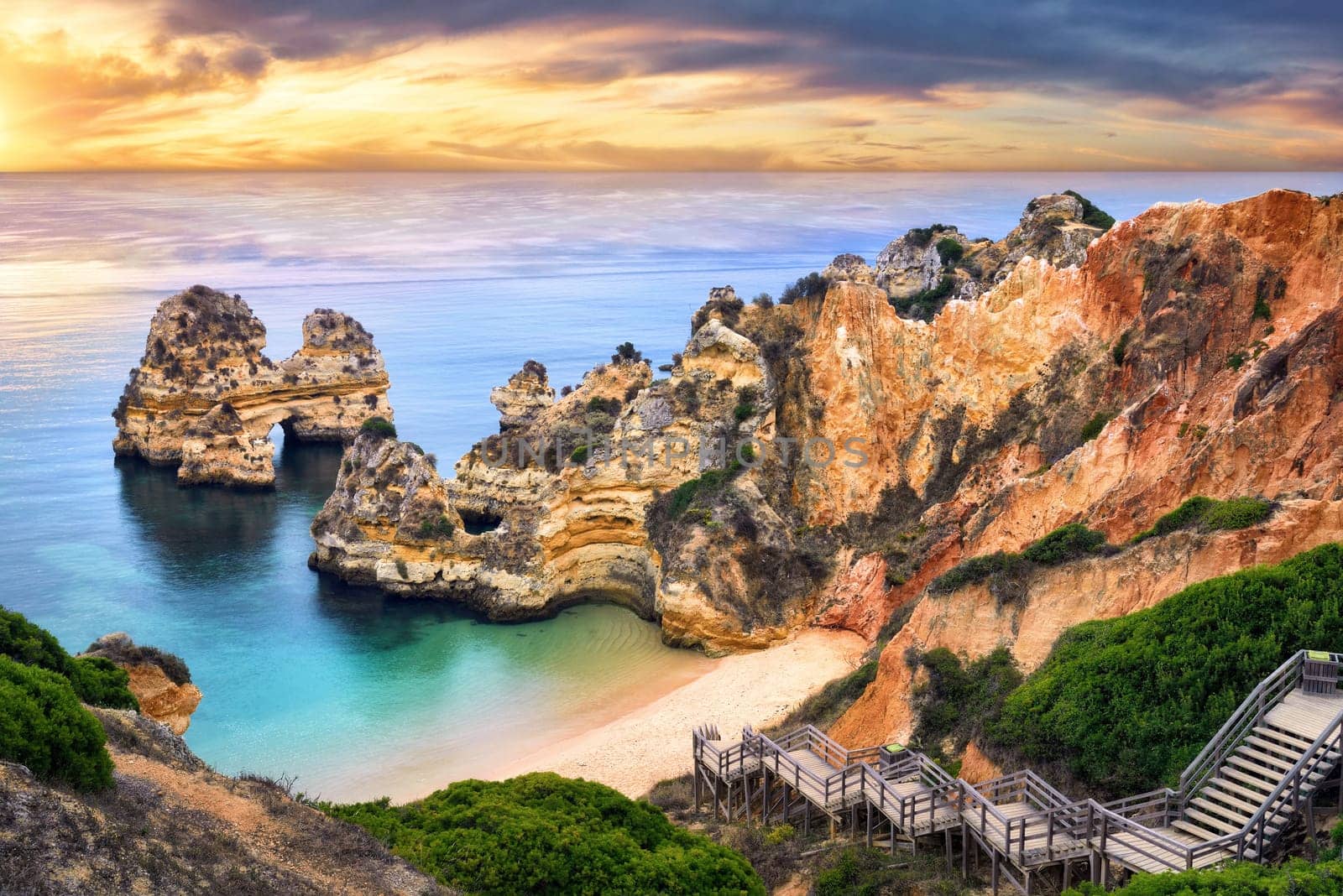 The beautiful Camilo Beach in Lagos,Portugal,with its magnificent cliffs and the blue ocean colorfully lit at sunrise