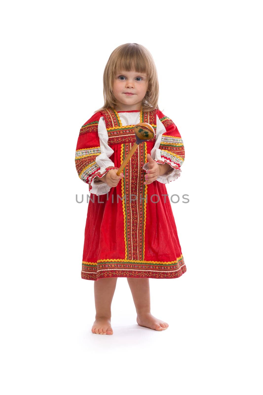 Little girl in red traditional dress with a wooden spoon. Isolate on white.