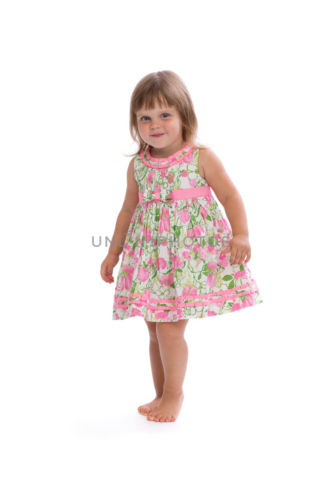 Charming little girl in a bright dress with a floral pattern. Isolate on white.
