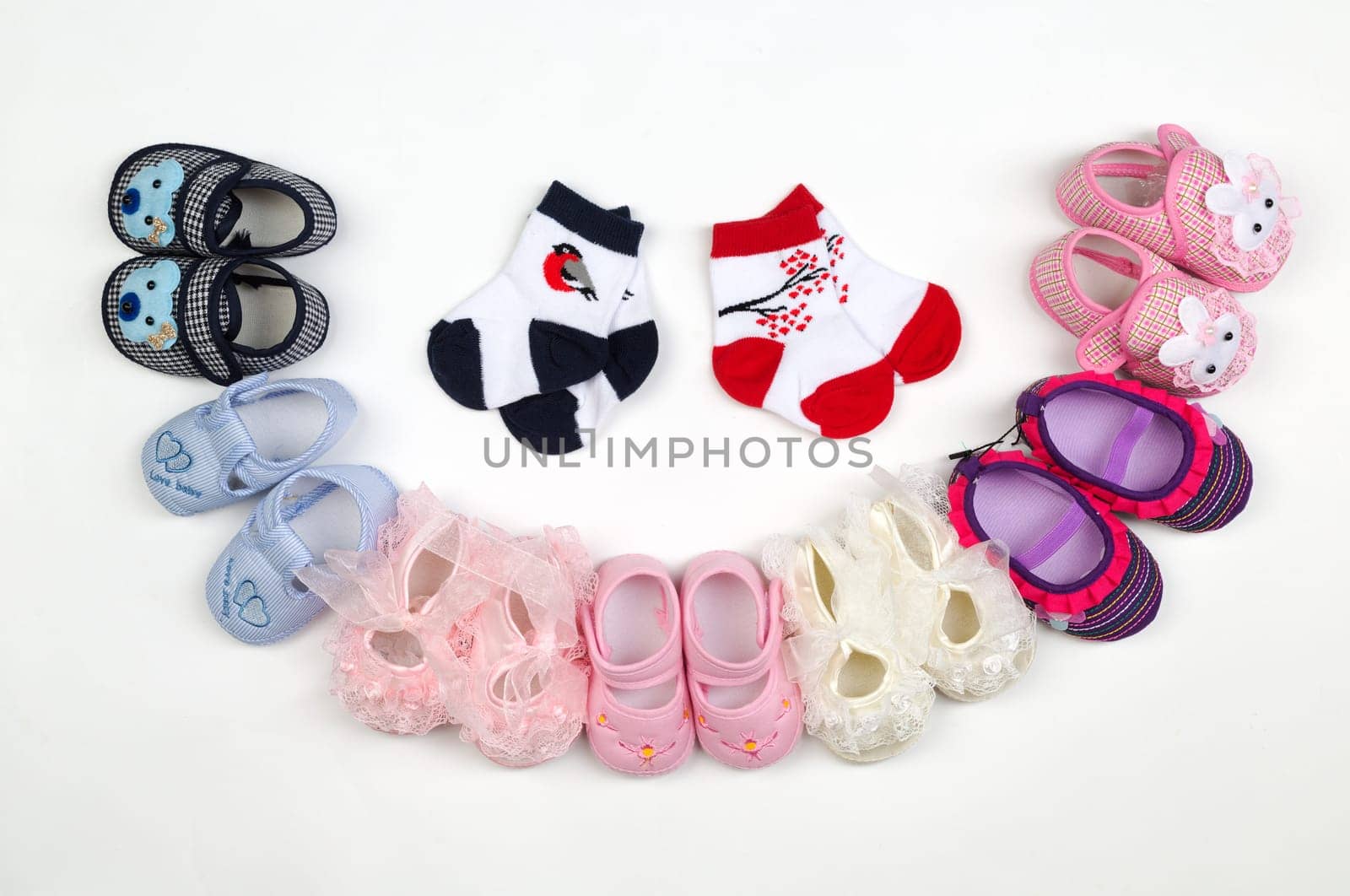 Children's shoes and socks laid semicircle on a light background.