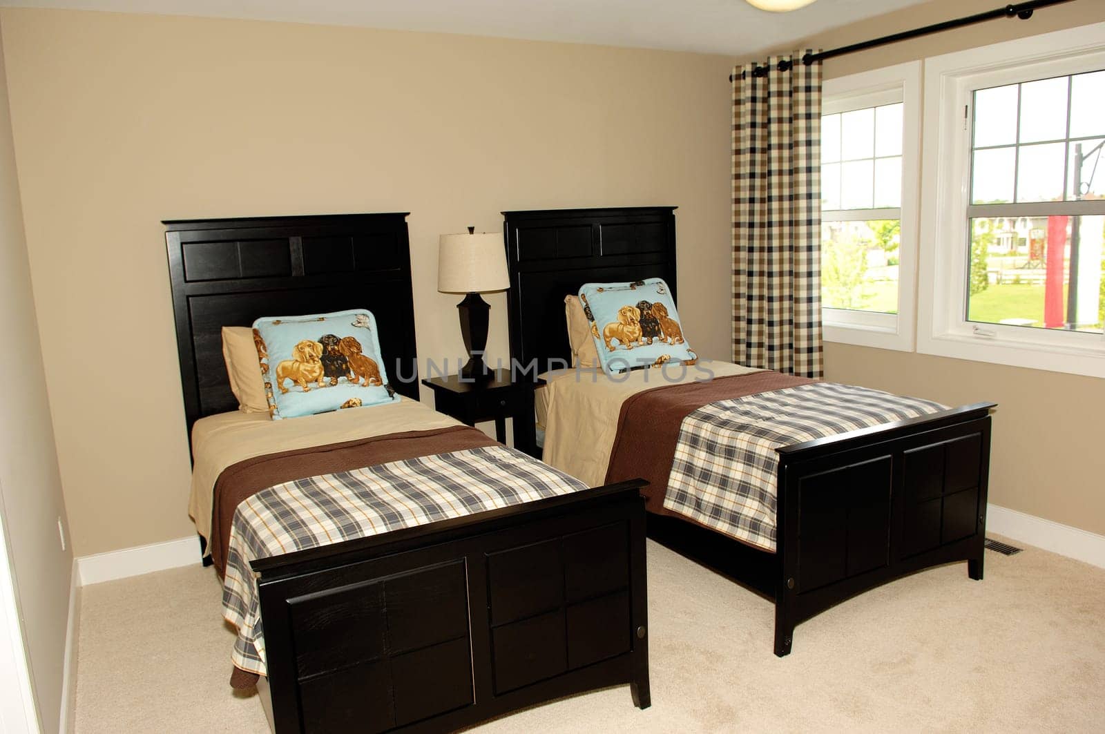 A bedroom in a new house with two single beds and large window's..