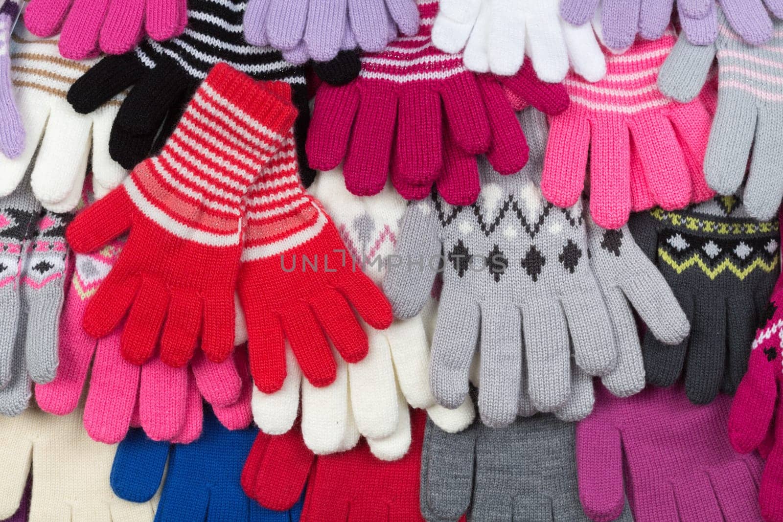 Colored knitted gloves stacked background.
