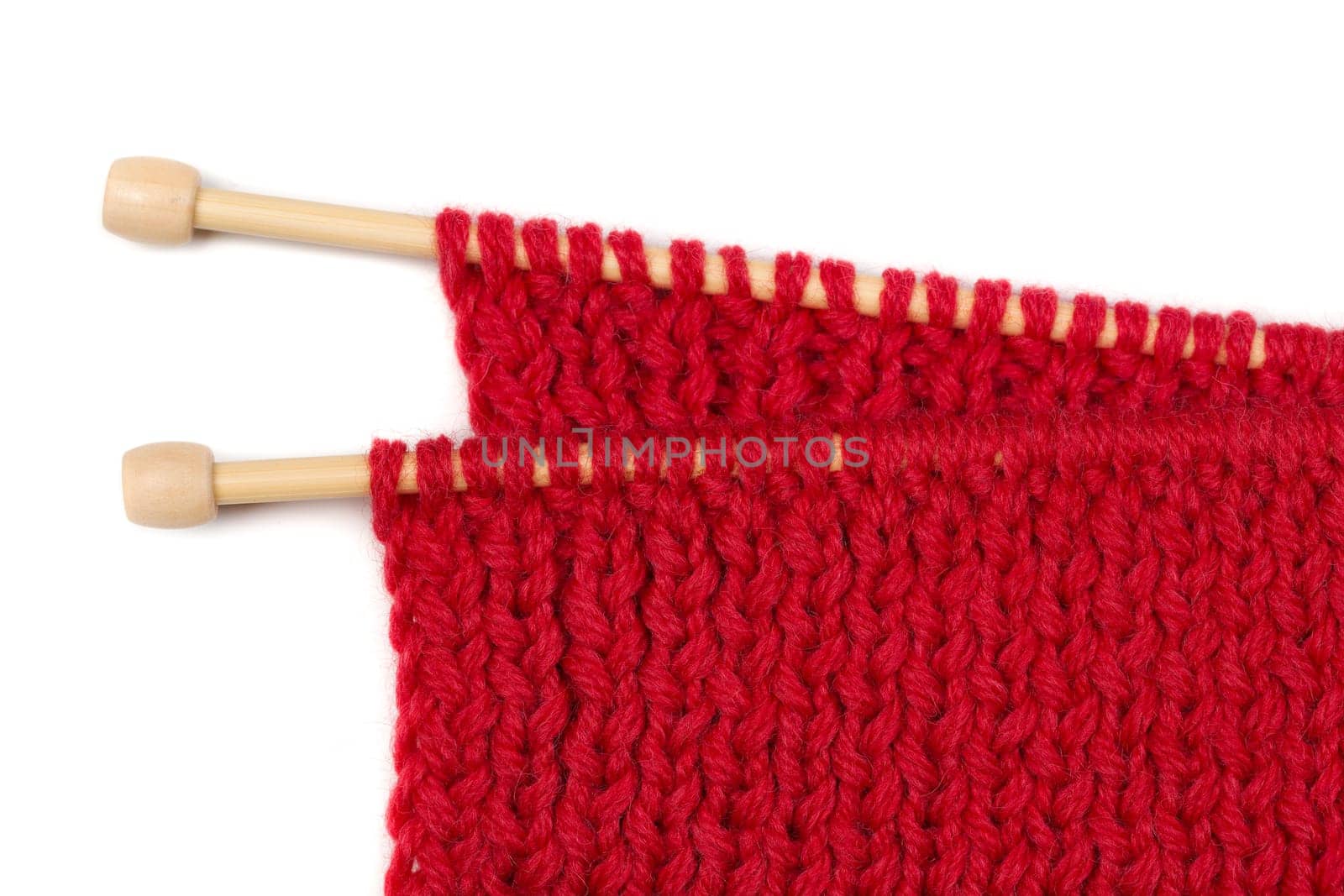 Red knitted wool fabric on wooden spokes. Isolate on white.