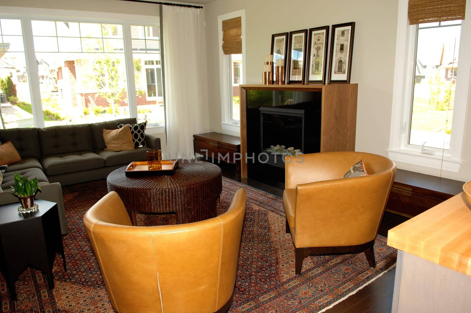 A nice living room in a new house with two windows, chairs and table.and a big area rug..