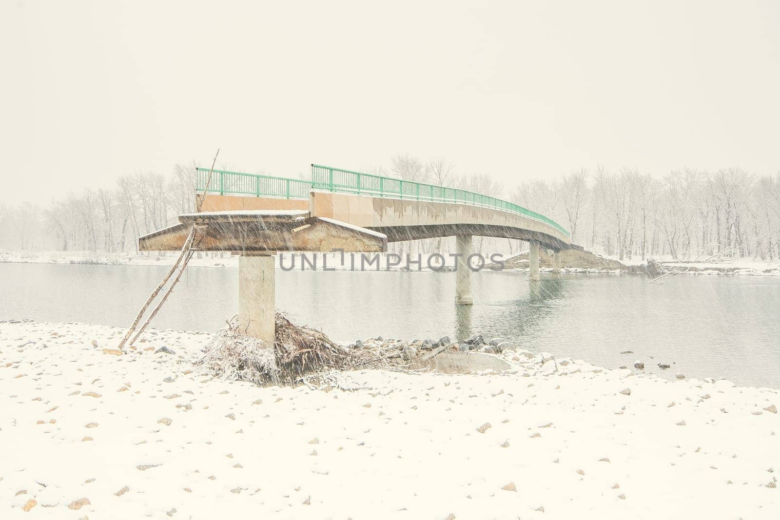 Landscape of an angled view of a flood damaged bridge in winter.